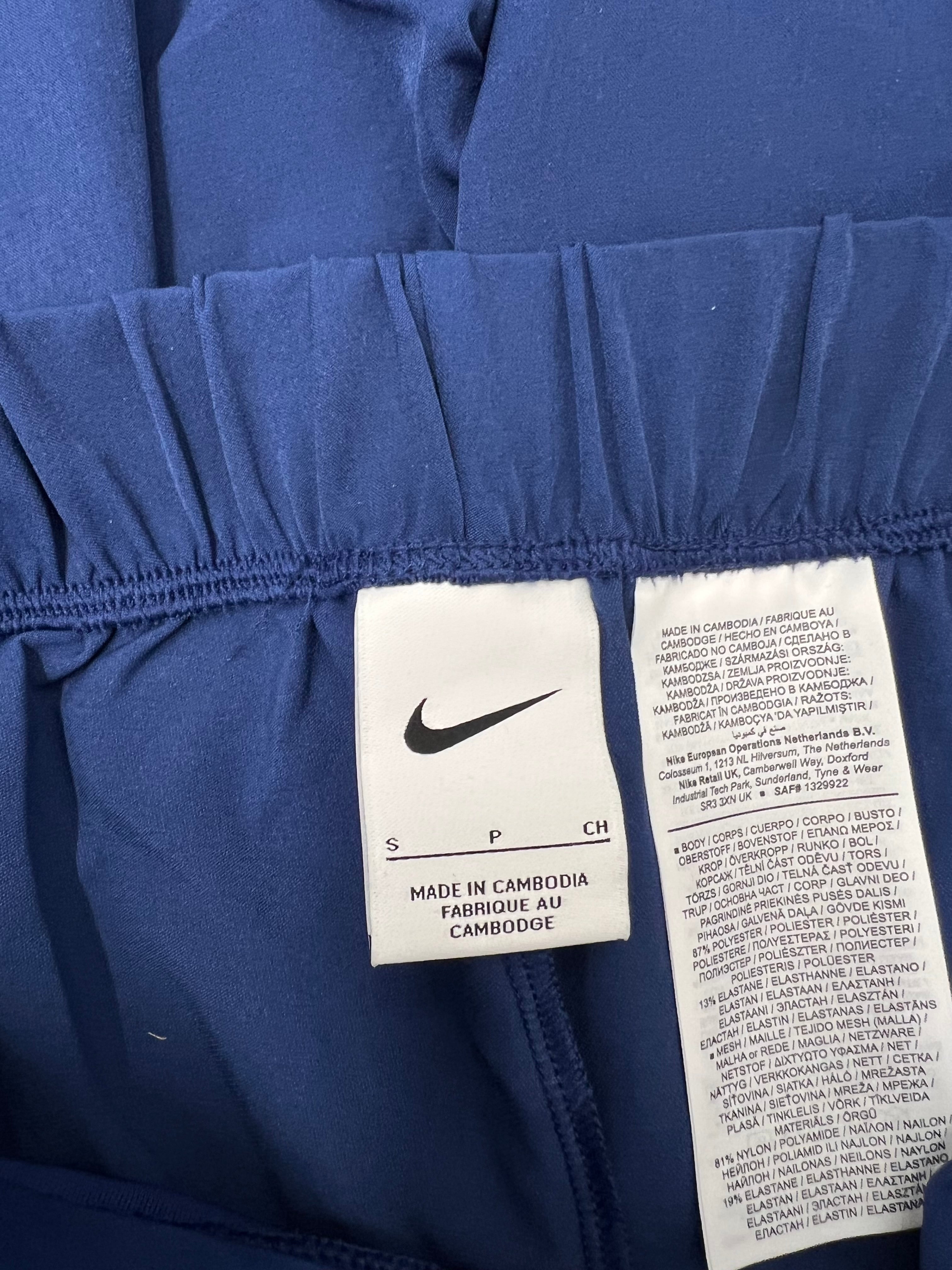 Close-up of interior label of blue Nike women's training pants showing size small and material composition