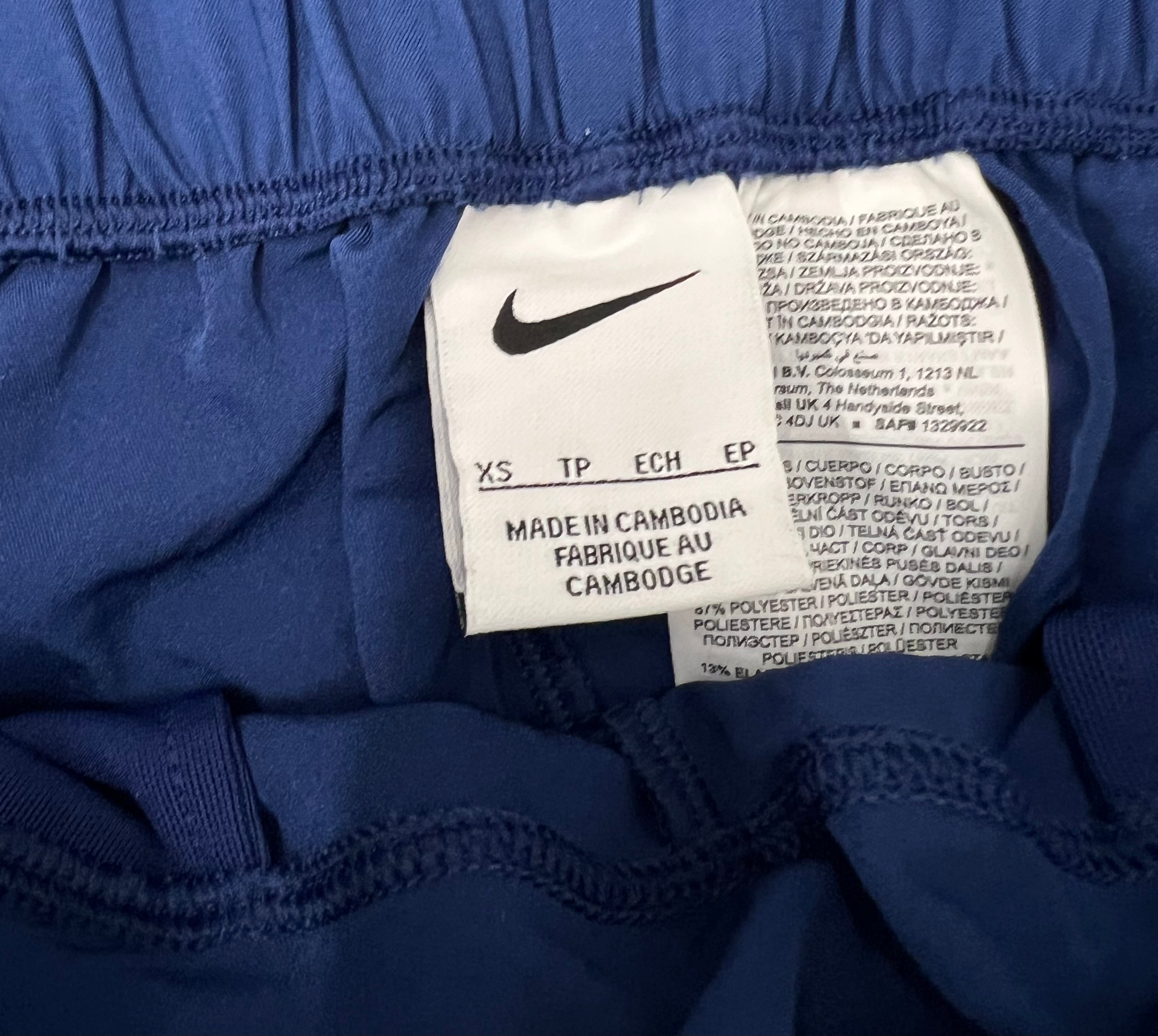Close-up of Nike label and fabric composition tag inside women's blue training pants