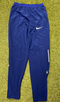 Nike women's blue Dri-FIT track pants front view laying flat on grass