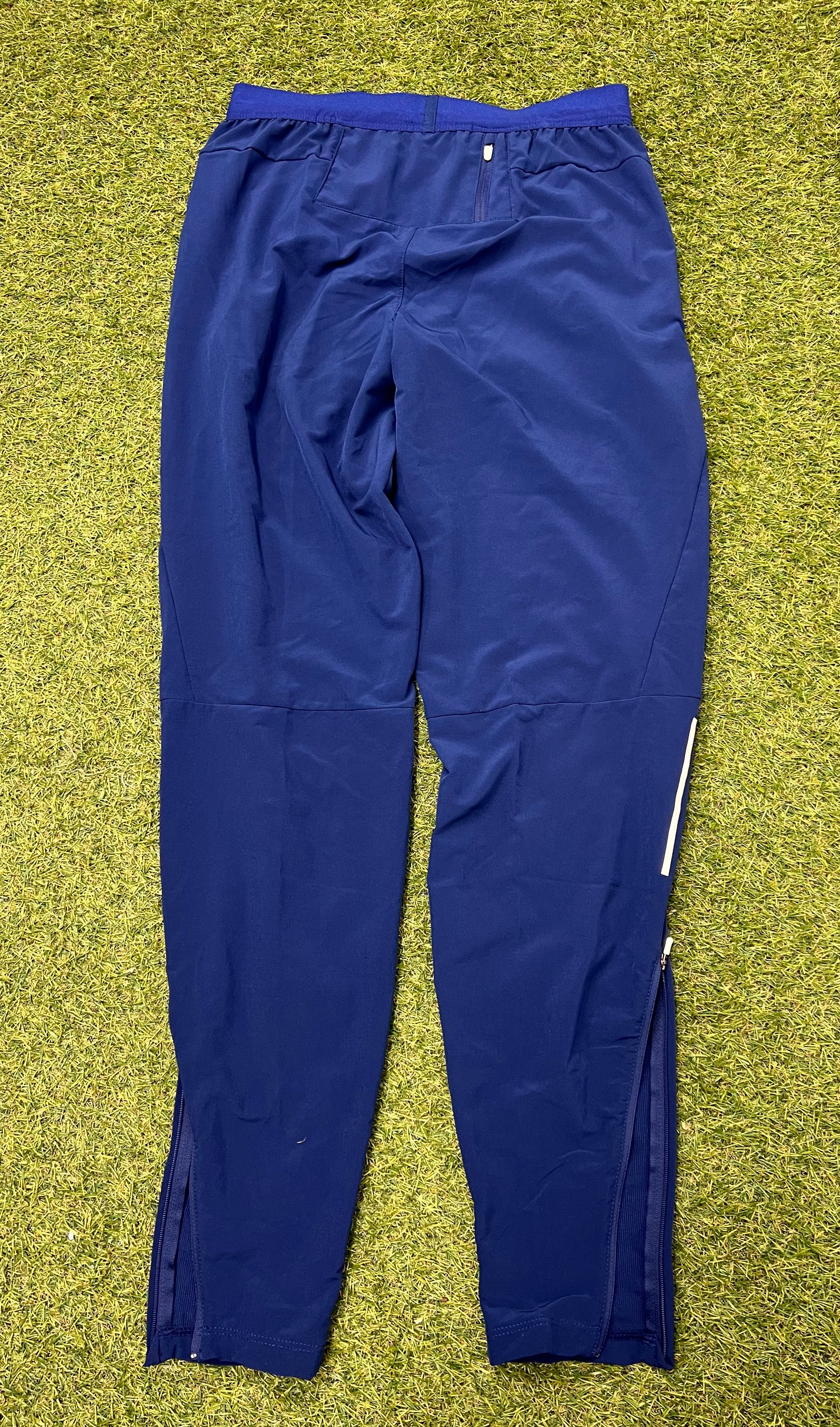Back view of Nike Women's navy blue Dri-FIT athletic track pants showing rear pockets and zippered ankle detail