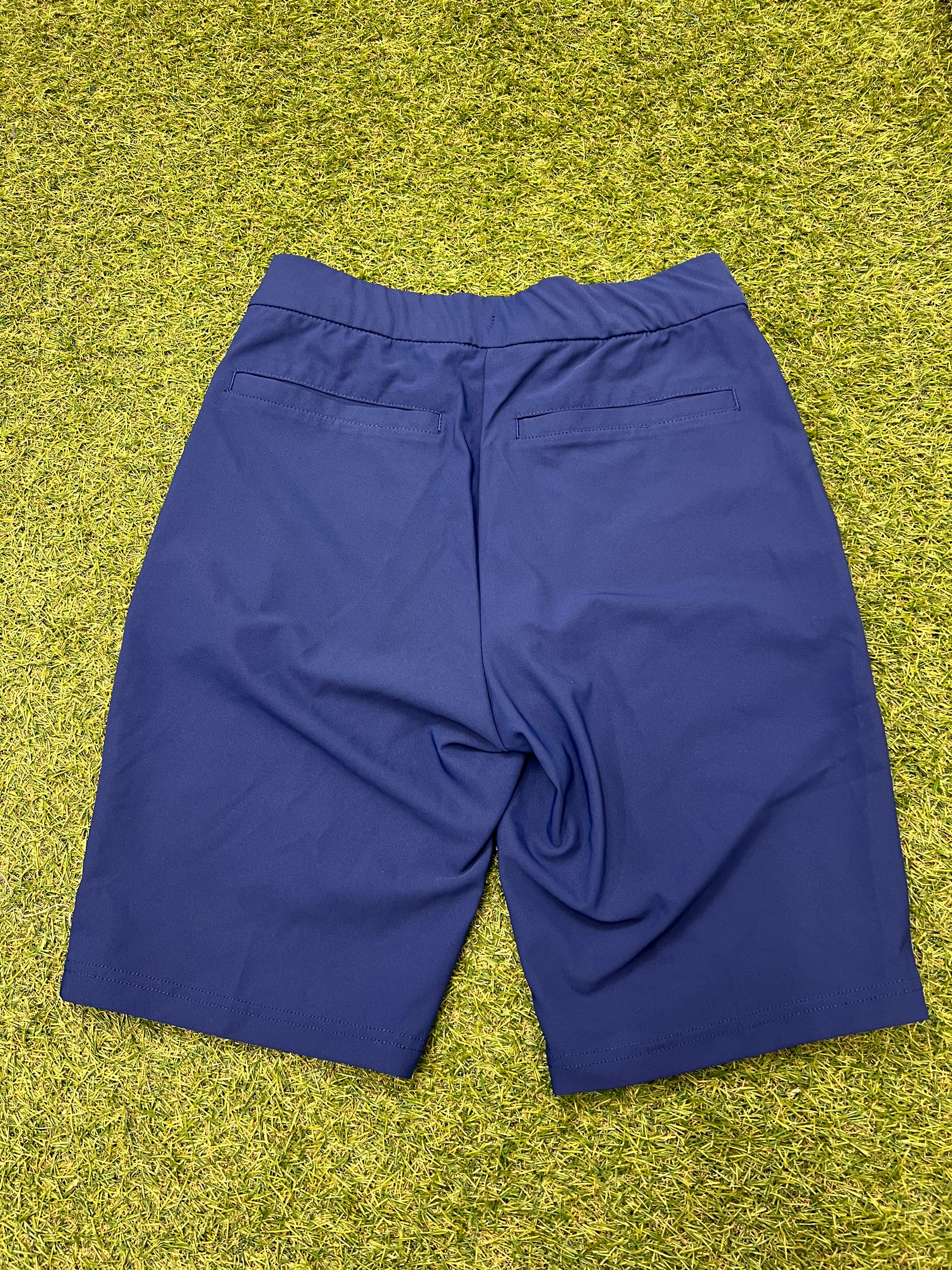 Rear view of Nike women's navy blue long line Dri-FIT shorts laid flat showing elastic waistband and back pockets.