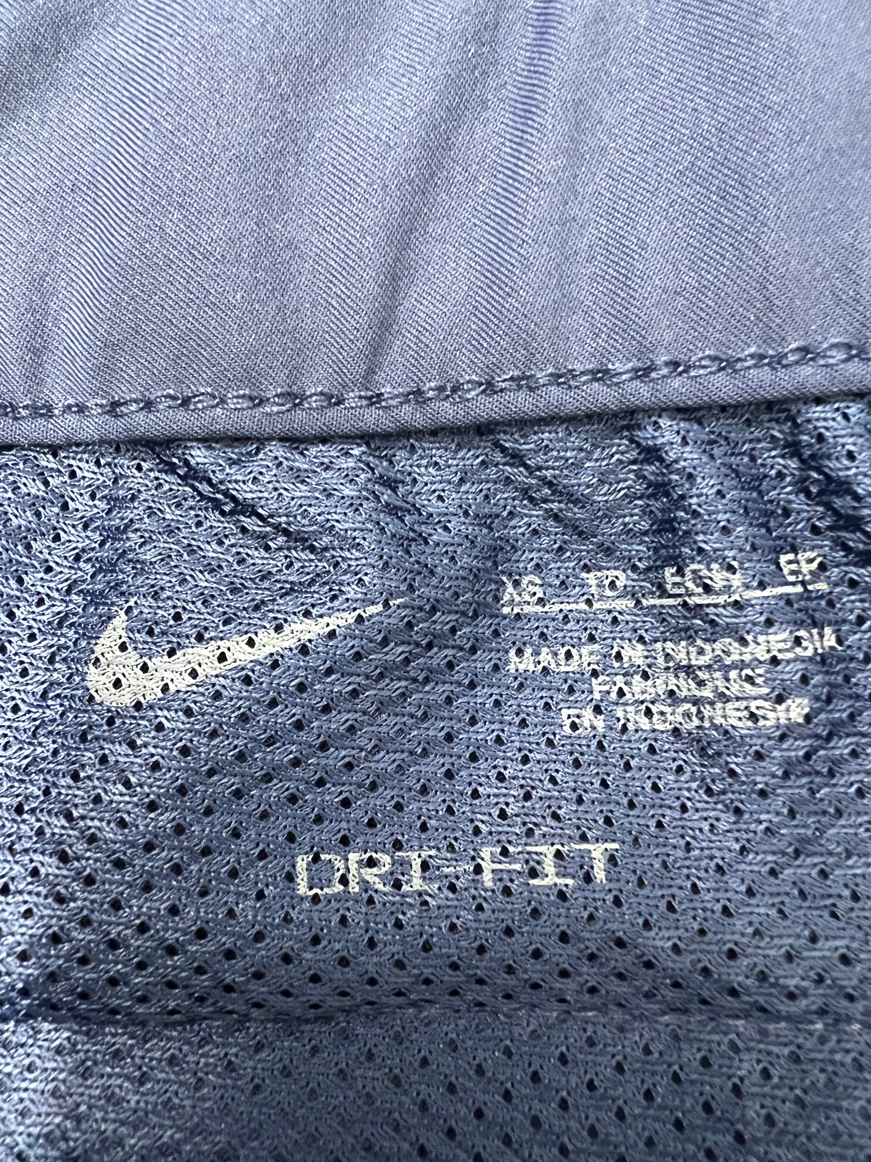Close-up of Nike Dri-FIT fabric label and inner mesh lining inside navy blue women's shorts.