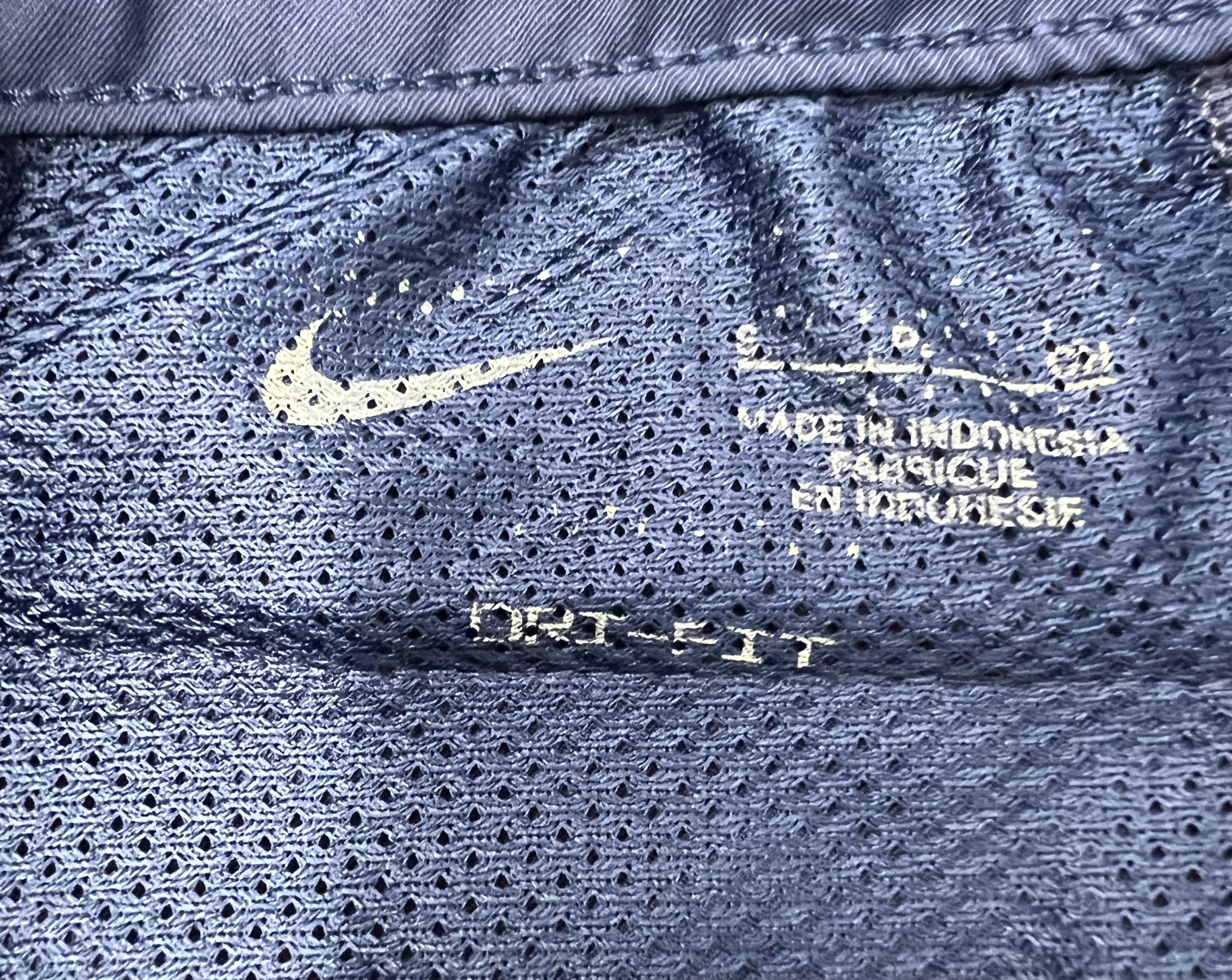 Close-up of inner label showing Nike logo, manufacturing details and Dri-FIT fabric technology on navy blue mesh lining