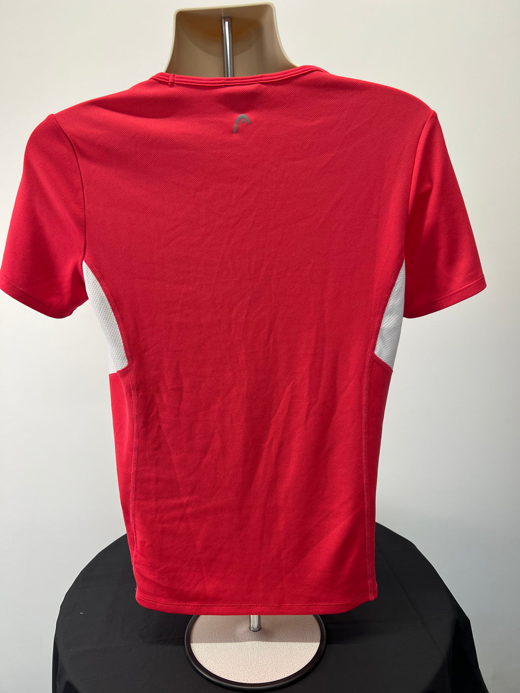 Back view of Head women's red sports t-shirt with white mesh side panels on a mannequin