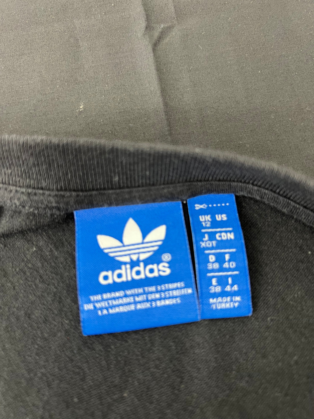 Close-up of Adidas blue size and brand tag inside neckline of black t-shirt