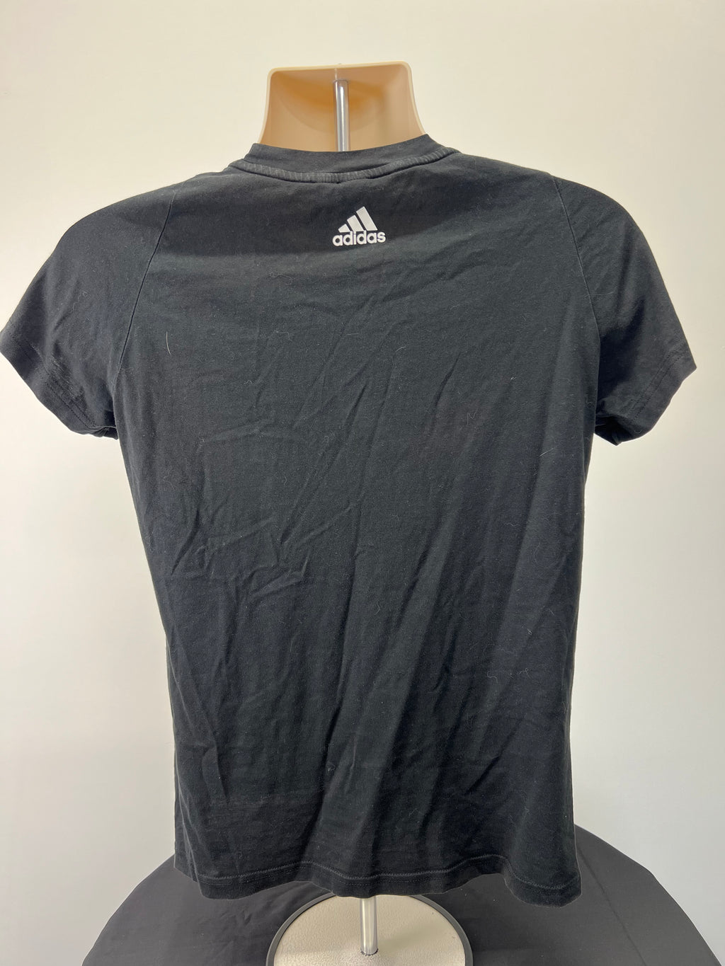 Back view of Adidas women's black t-shirt showing small Adidas logo below neckline.