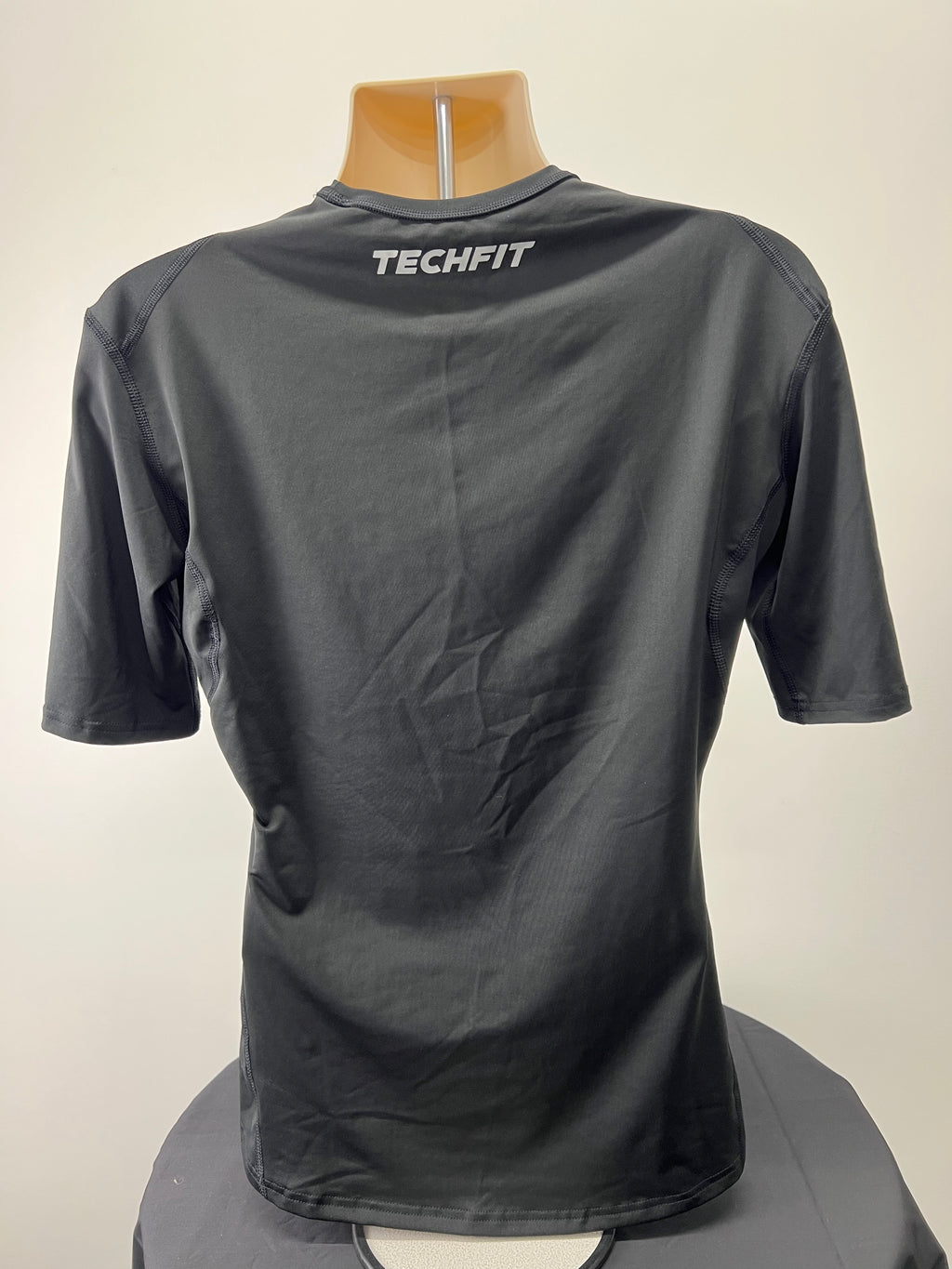 Back view of black Adidas Techfit compression short sleeve t-shirt with TECHFIT branding on upper back