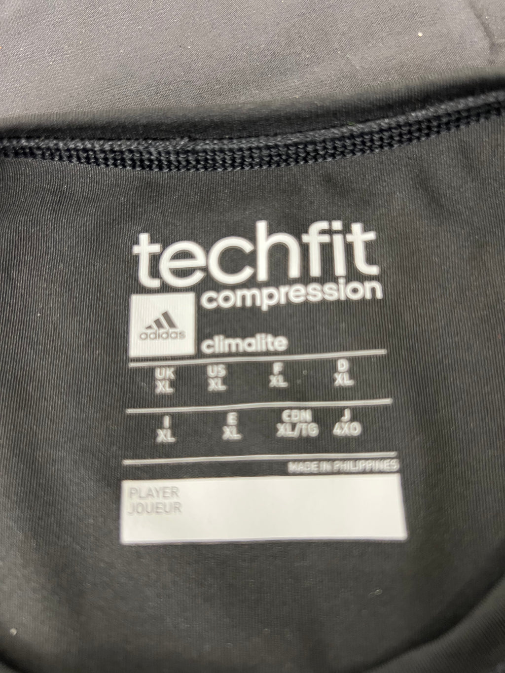 Close-up of Adidas Techfit compression t-shirt internal label showing size XL and Climalite fabric technology