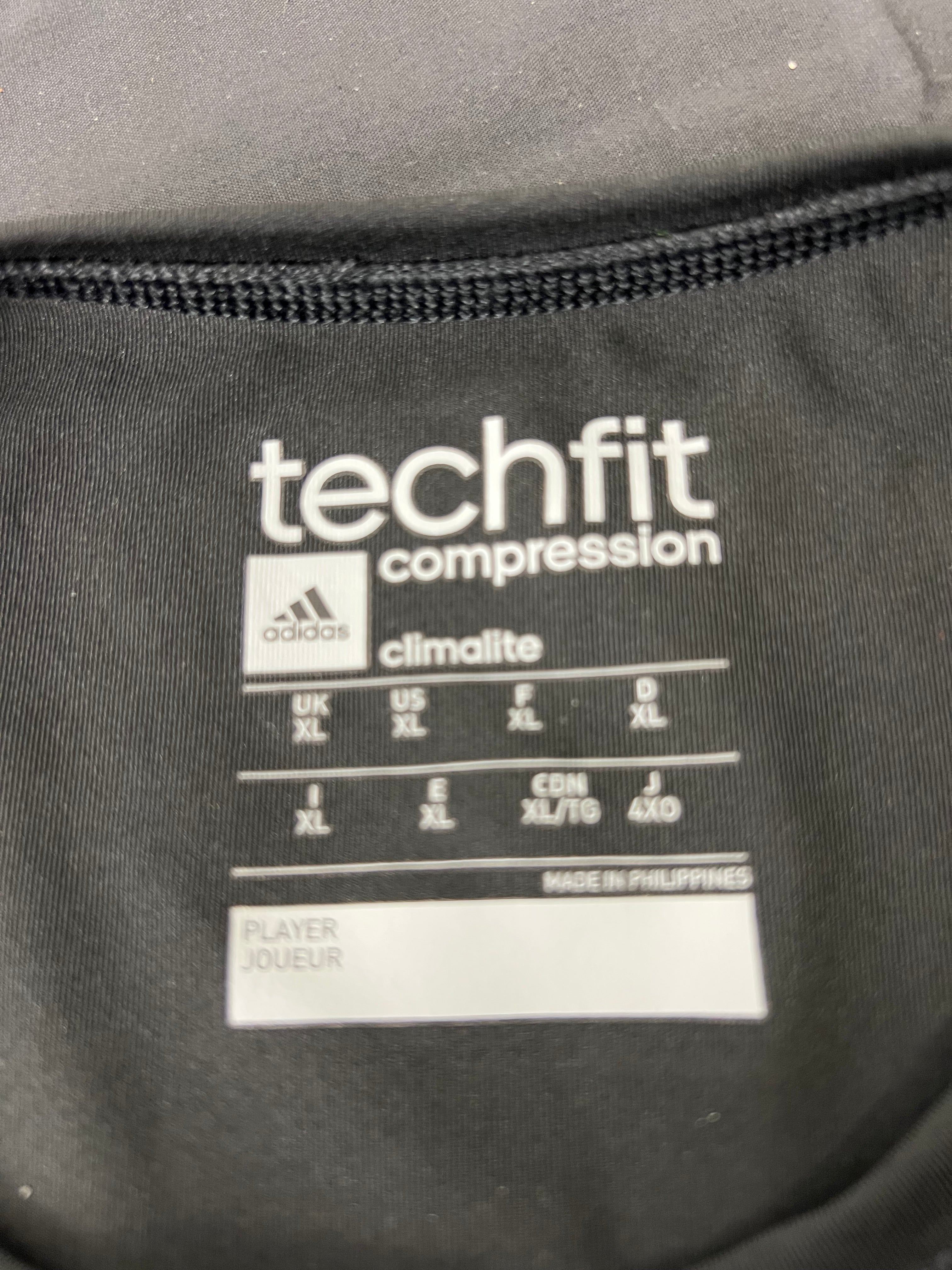 Close-up of Adidas Techfit compression t-shirt internal label showing size XL and Climalite fabric technology