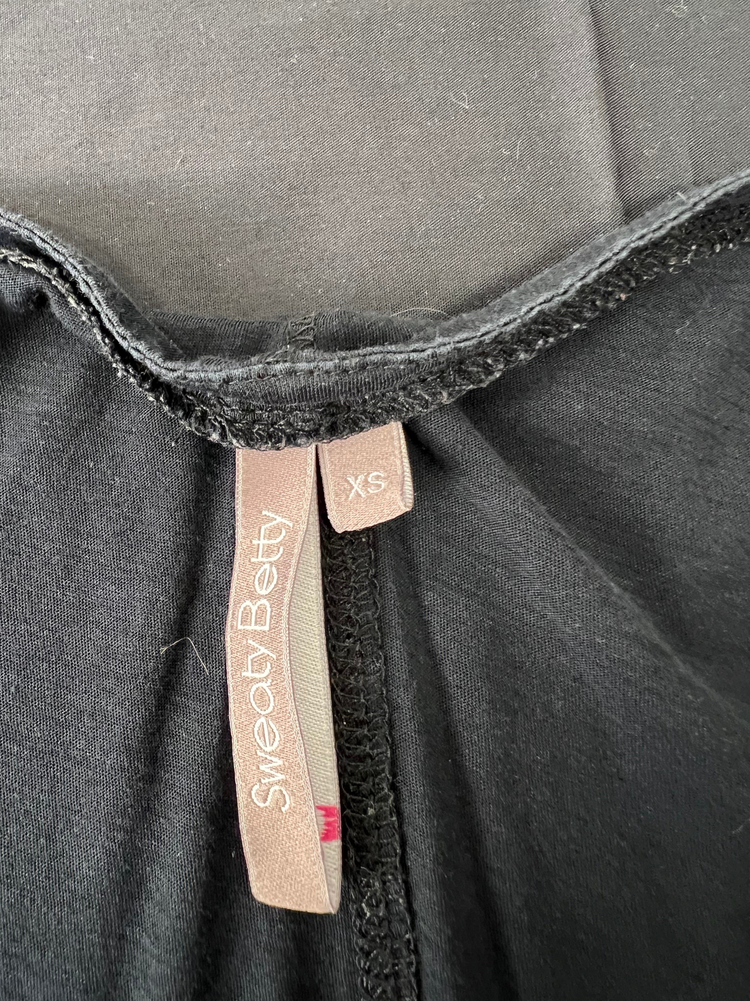 Close-up of the Sweaty Betty label and size XS tag inside the black V-neck T-shirt