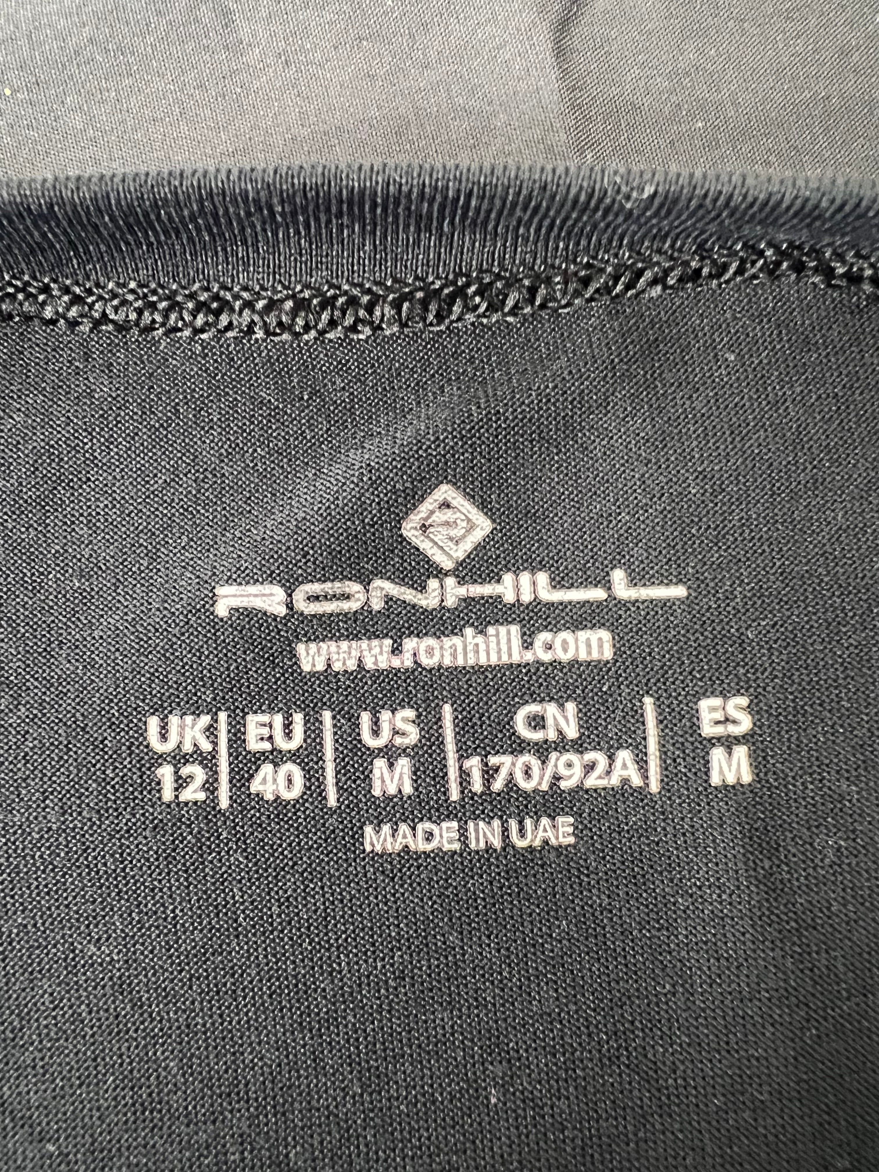 Close-up of Ronhill label inside black t-shirt showing size UK 12 EU 40 US M and manufacturing details