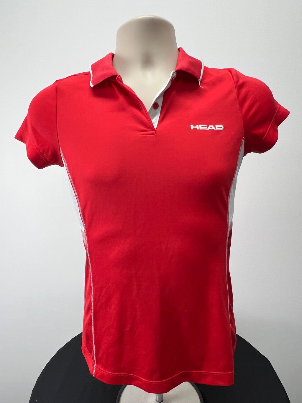 Front view of HEAD women's red polo shirt with white piped collar and short sleeves on mannequin