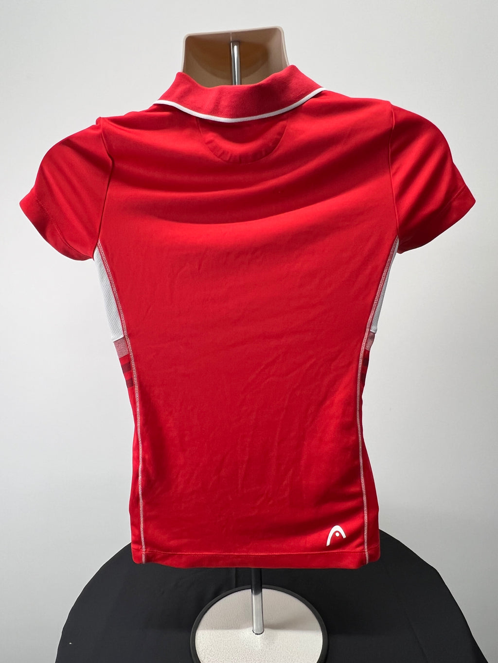 Back view of HEAD women's red polo shirt showing solid red design with white mesh side panels on mannequin