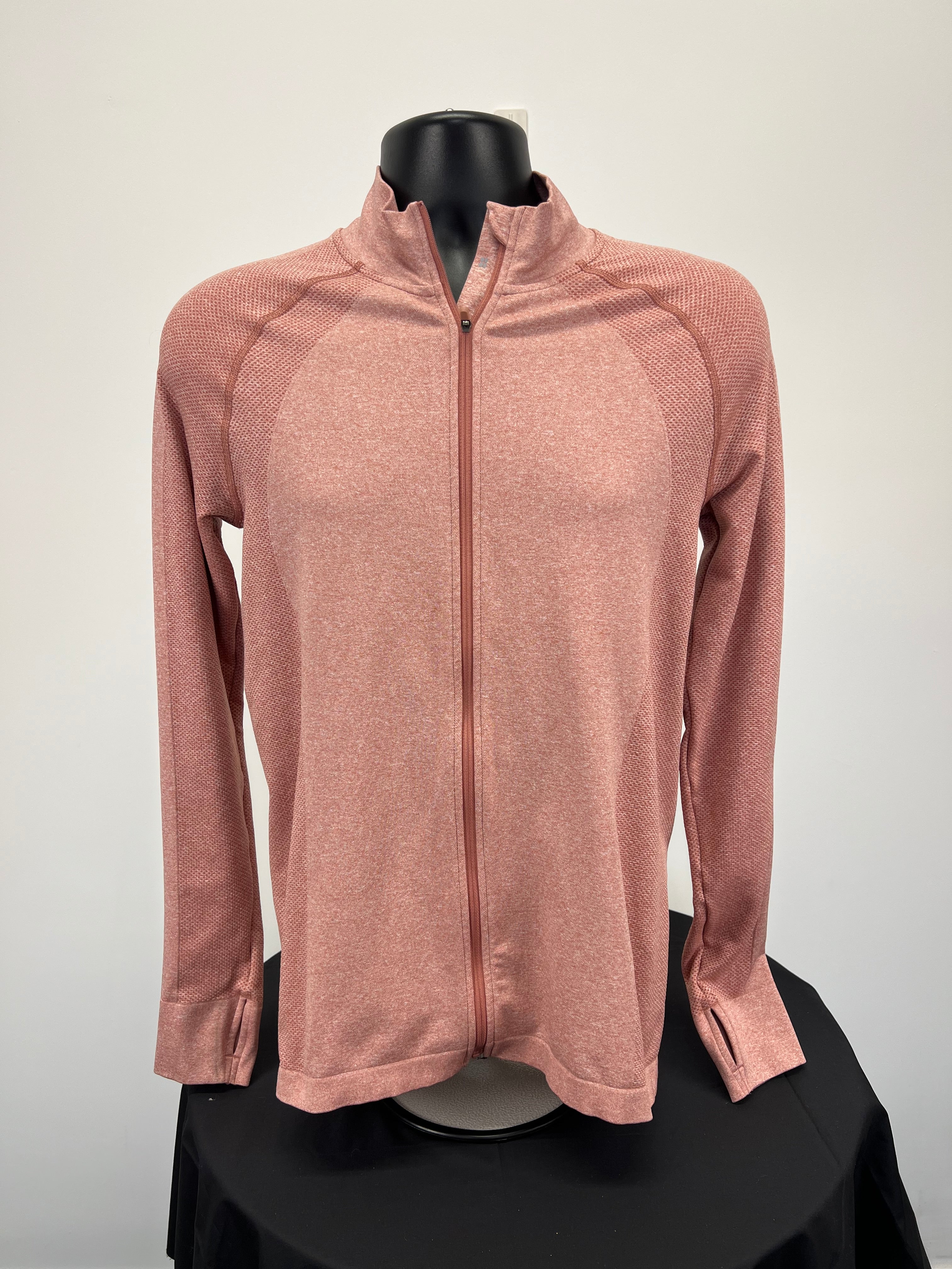 Front view of peach coloured Sweaty Betty full zip active jacket with textured panels and thumb holes on sleeves