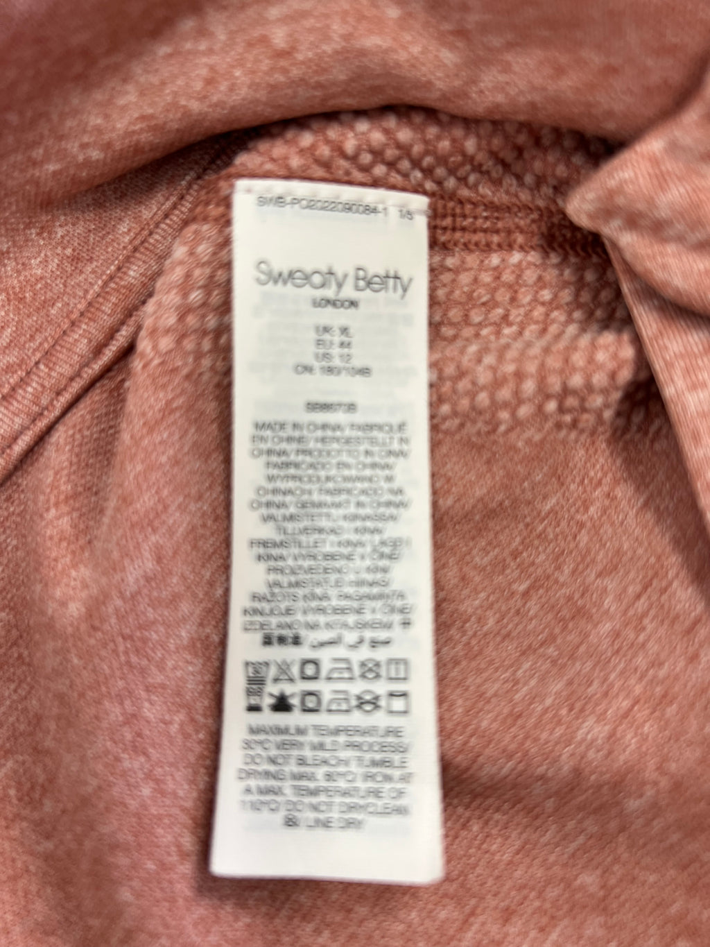 Close-up of Sweaty Betty label and care instructions inside the peach active jacket
