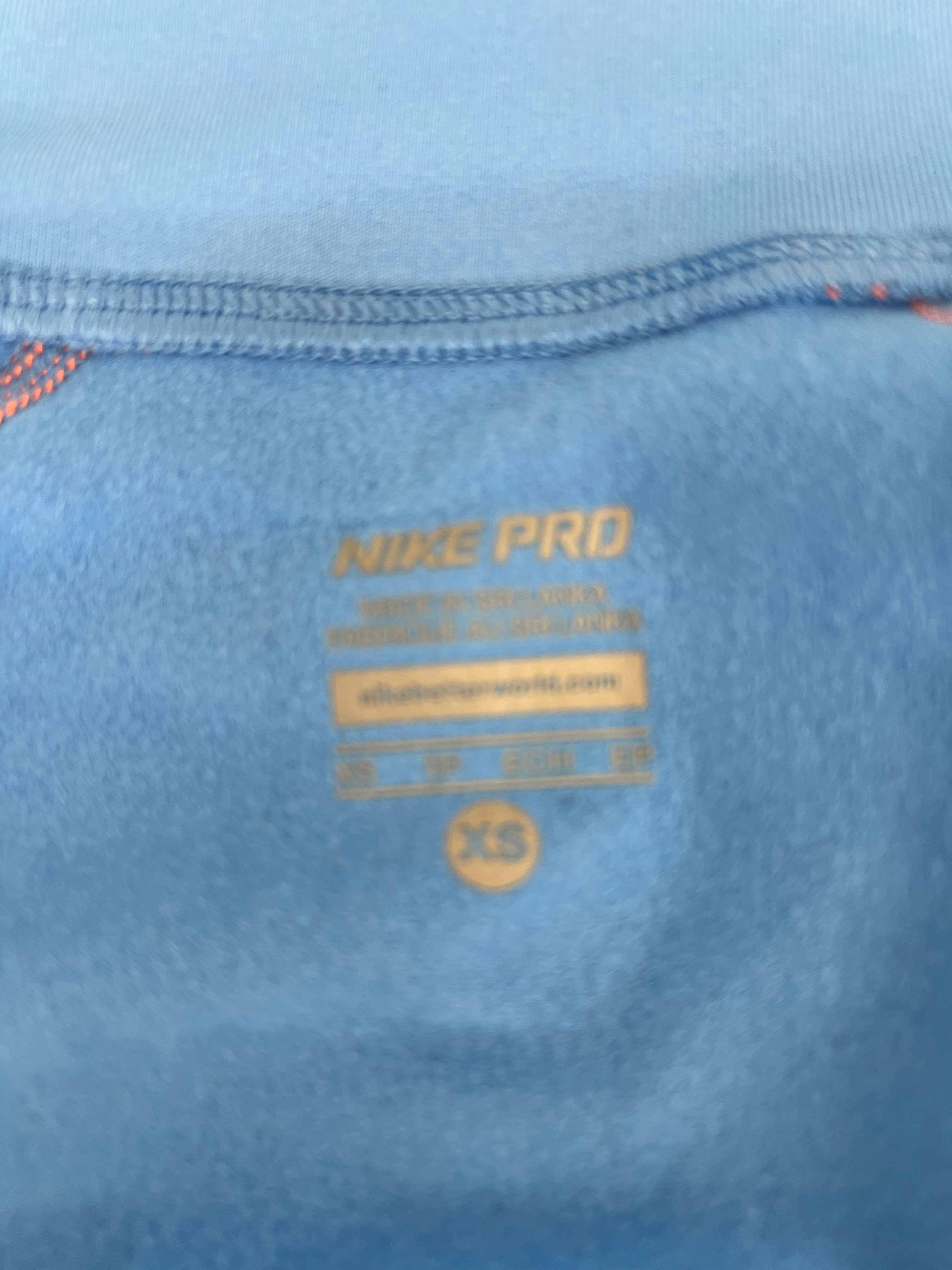 Close-up of printed size label inside blue Nike Pro top indicating XS size made in Sri Lanka