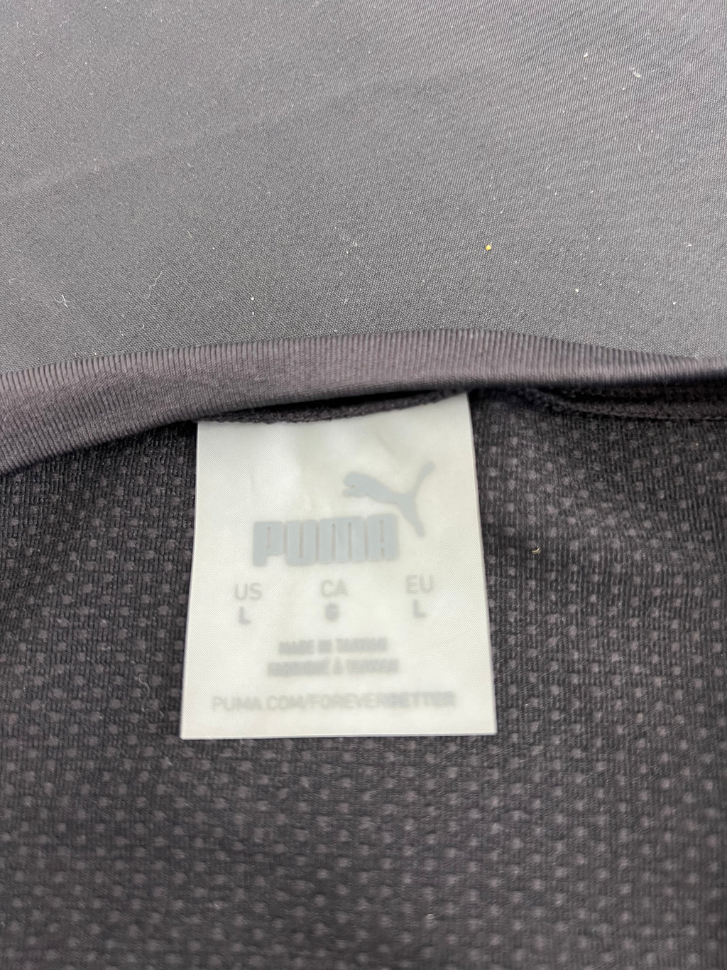 Close-up of Puma brand tag inside black mesh crop top showing size and care information