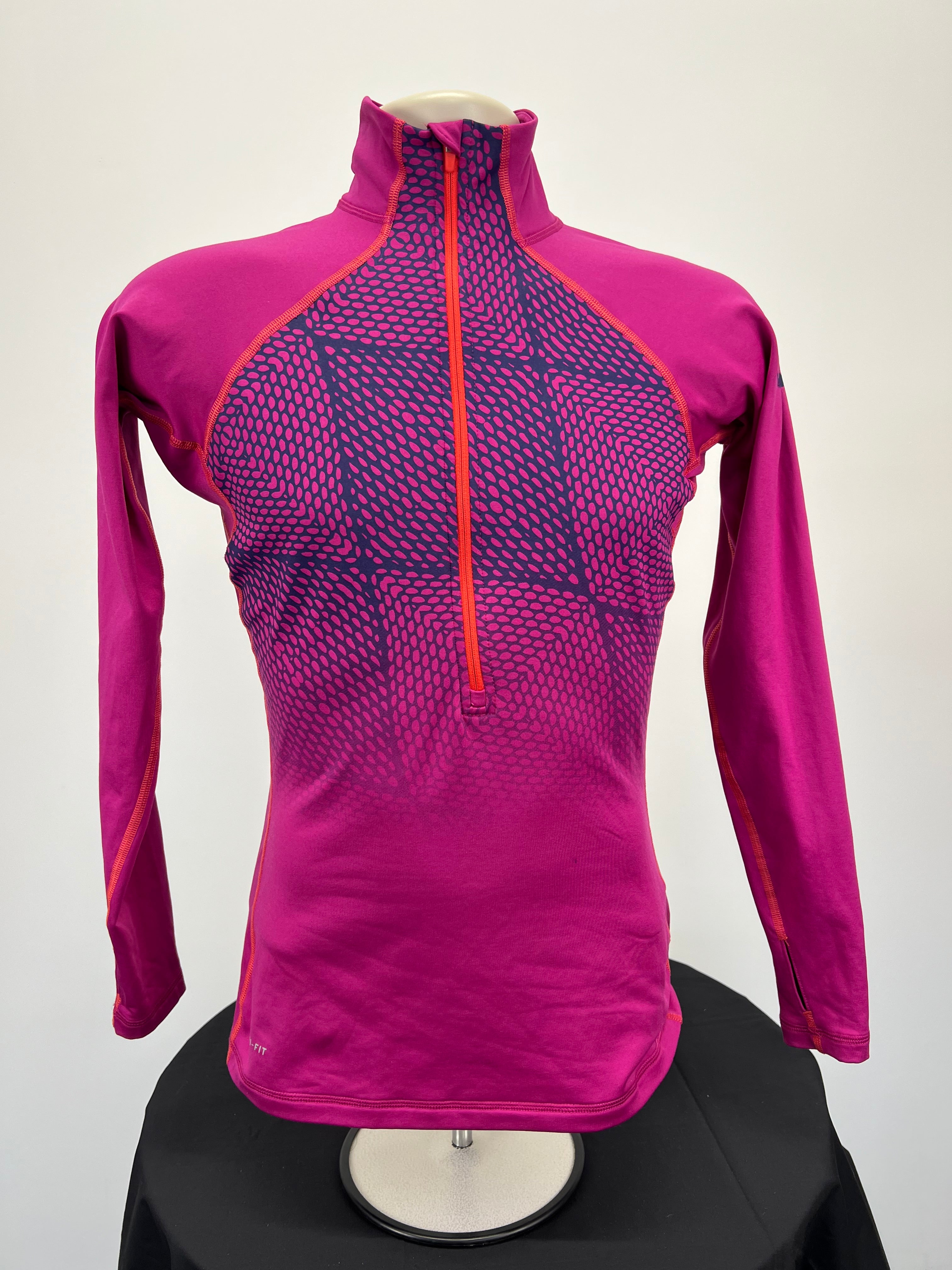 Front view of Nike Pro women's long sleeve half-zip performance top in magenta with geometric pink and navy pattern on chest