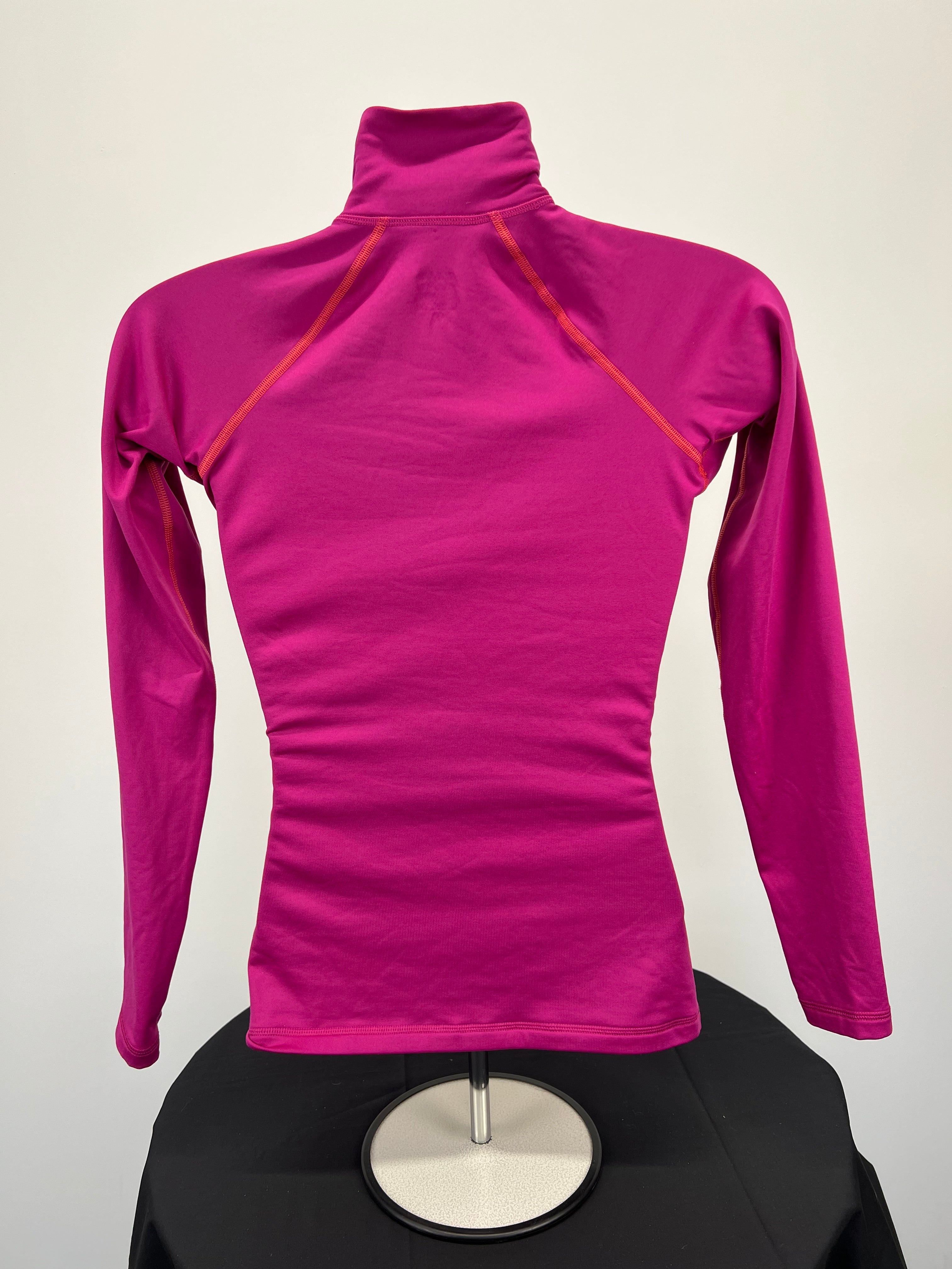 Back view of Nike Pro women's long sleeve half-zip top in solid magenta with visible orange stitching on raglan seams