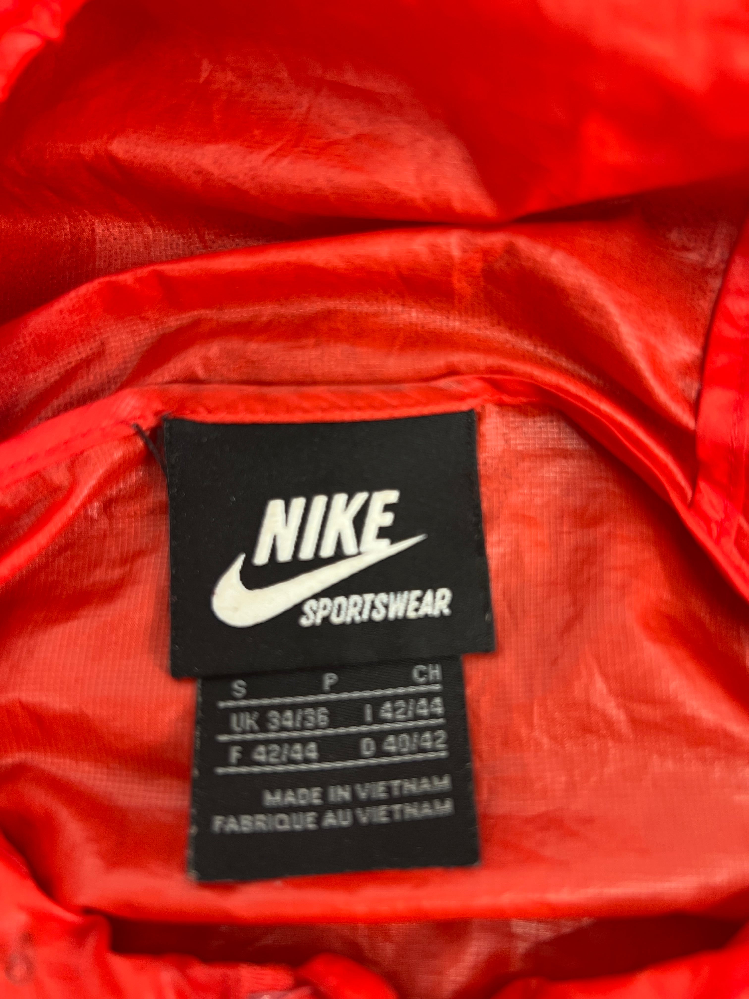 Close-up image of Nike Sportswear brand label with size information inside the red lightweight jacket