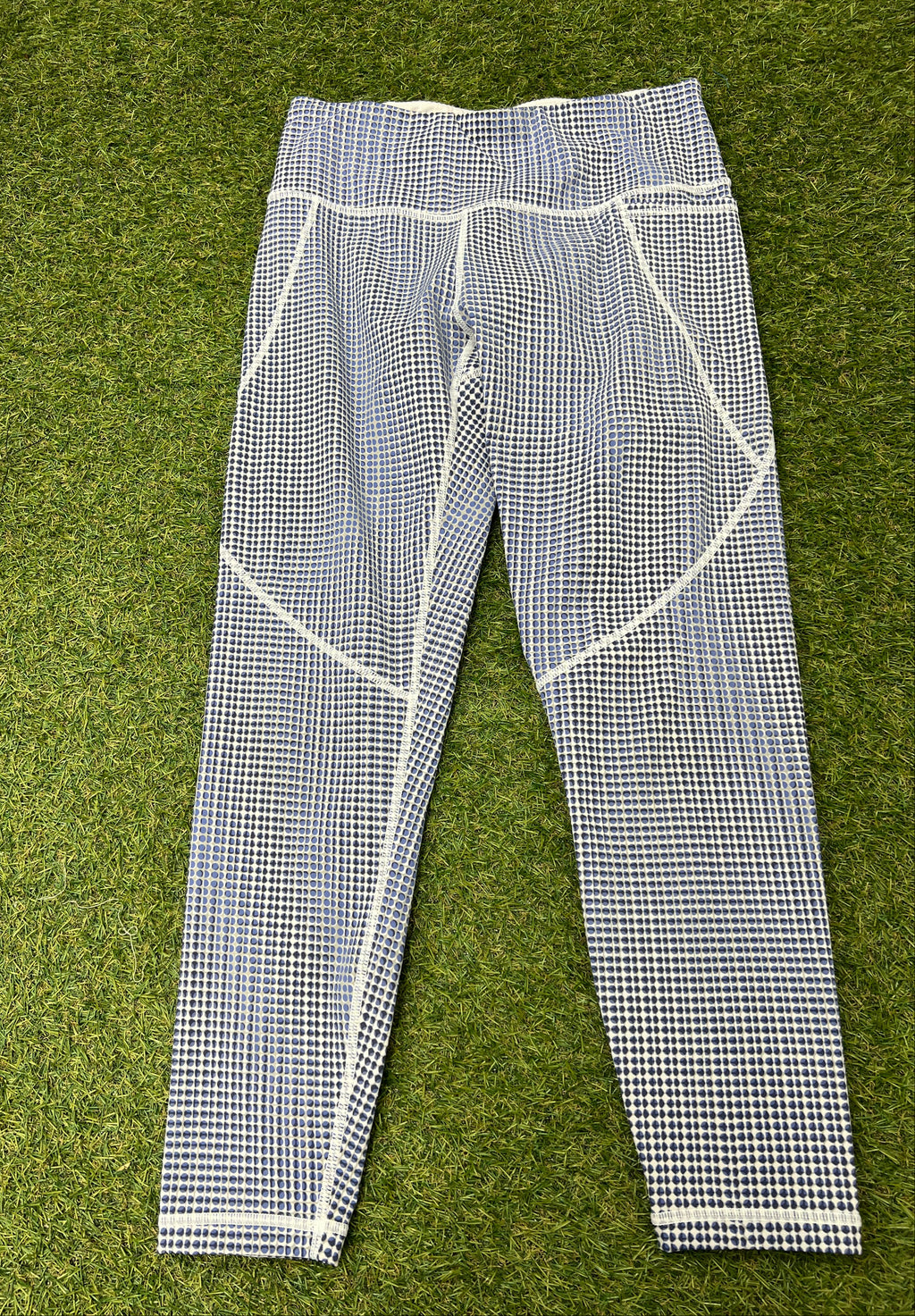Front view of Sweaty Betty Power 7/8 length leggings with blue and white spotted pattern laid flat on grass