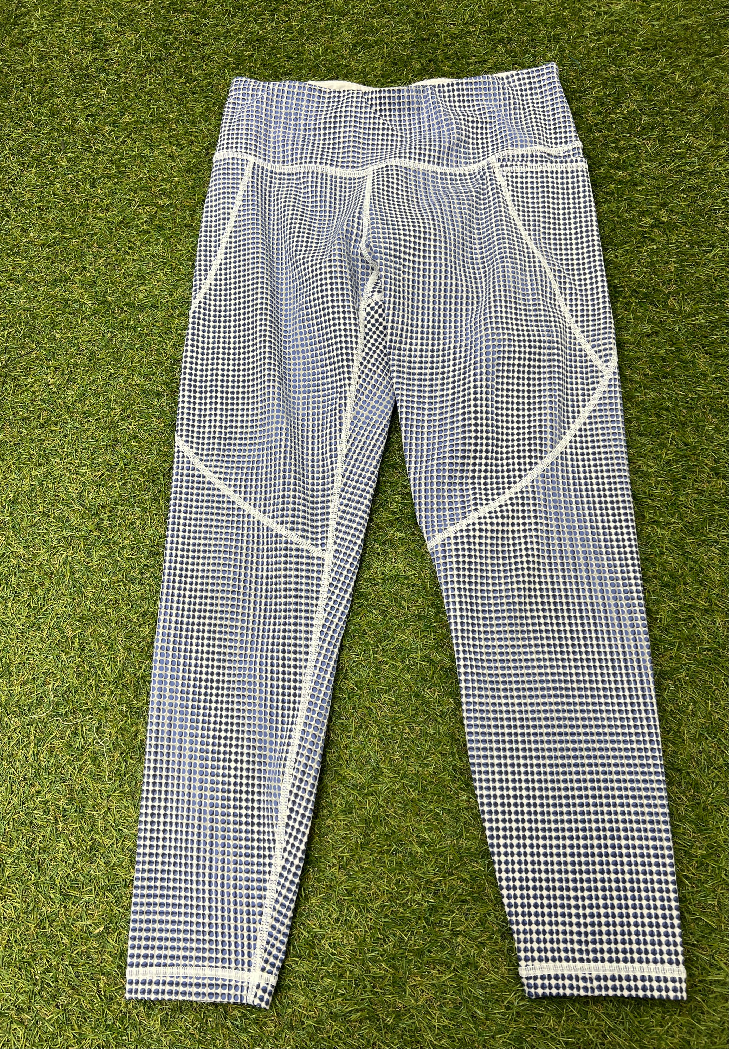 Front view of Sweaty Betty Power 7/8 length leggings with blue and white spotted pattern laid flat on grass