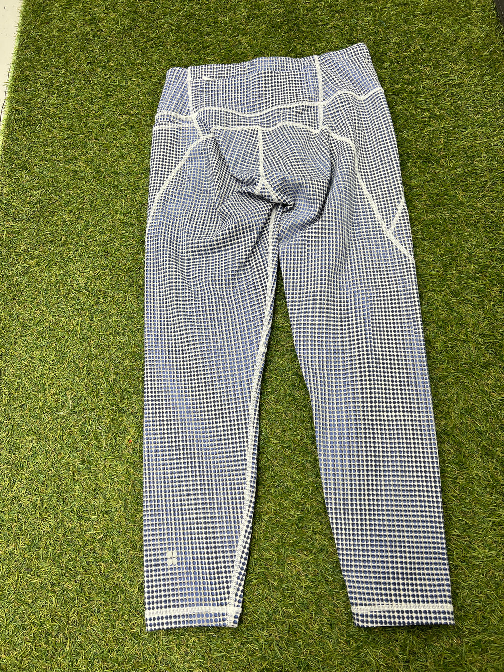 Back view of the same blue and white spotted 7/8 leggings displayed on grass showing seam details and fit