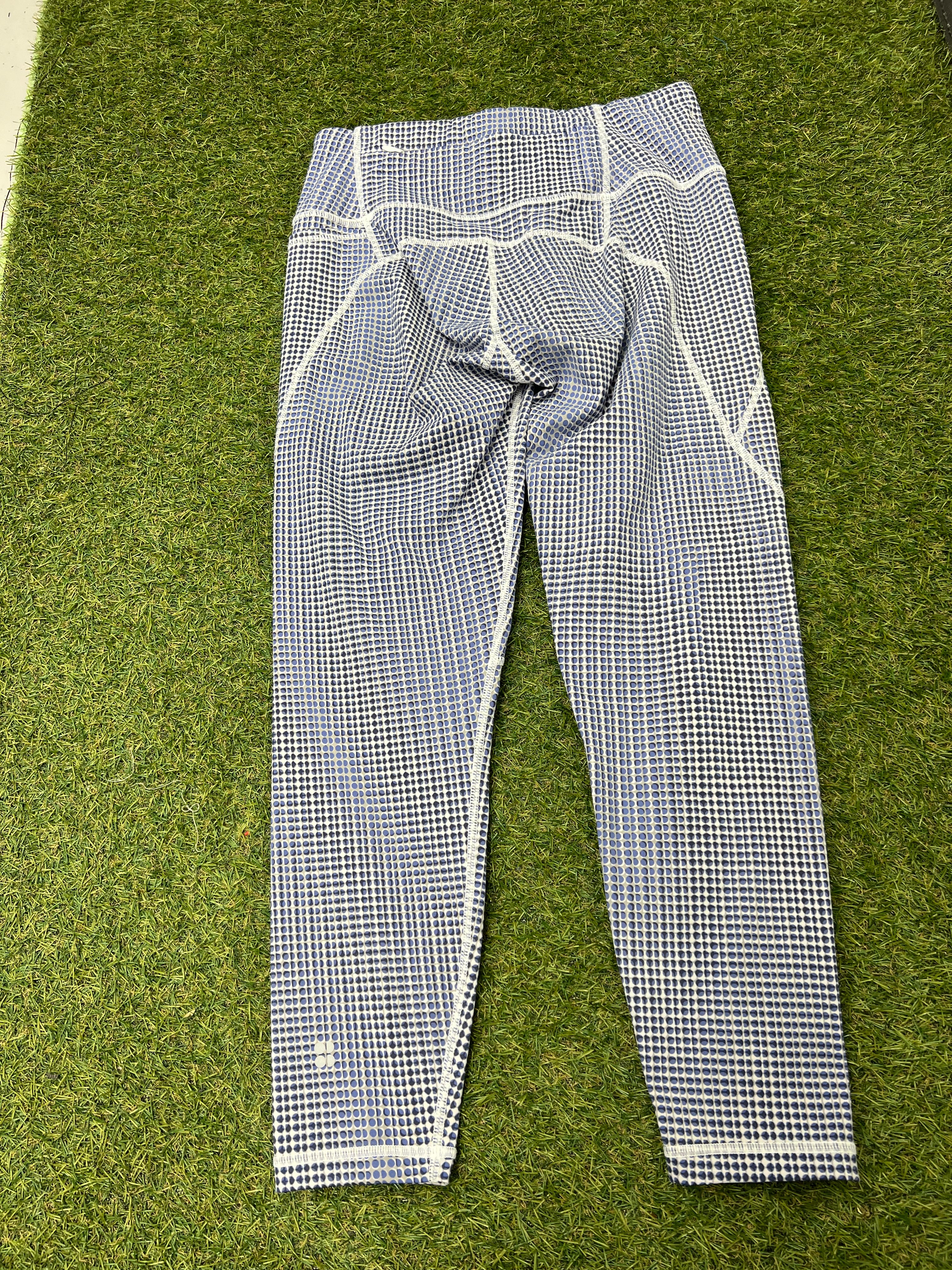 Back view of the same blue and white spotted 7/8 leggings displayed on grass showing seam details and fit