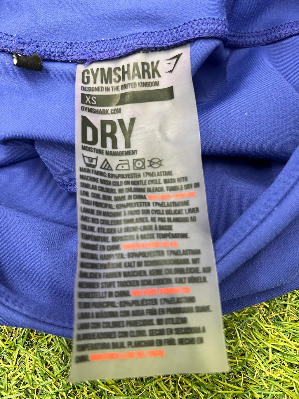 Close-up image of Gymshark label inside blue leggings showing fabric and care instructions