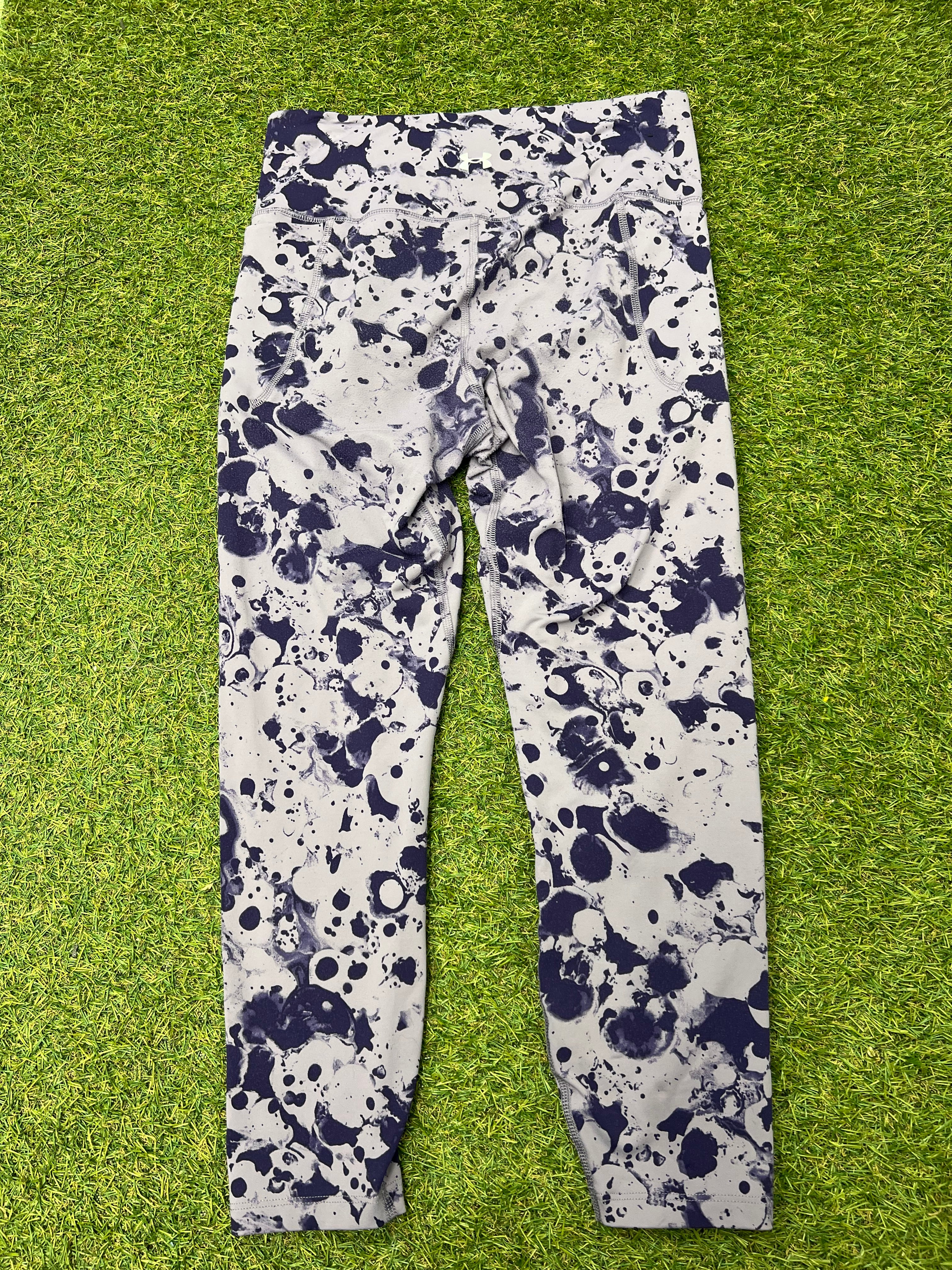 Back view of Under Armour fitted leggings showing the same splash pattern laid flat on grass