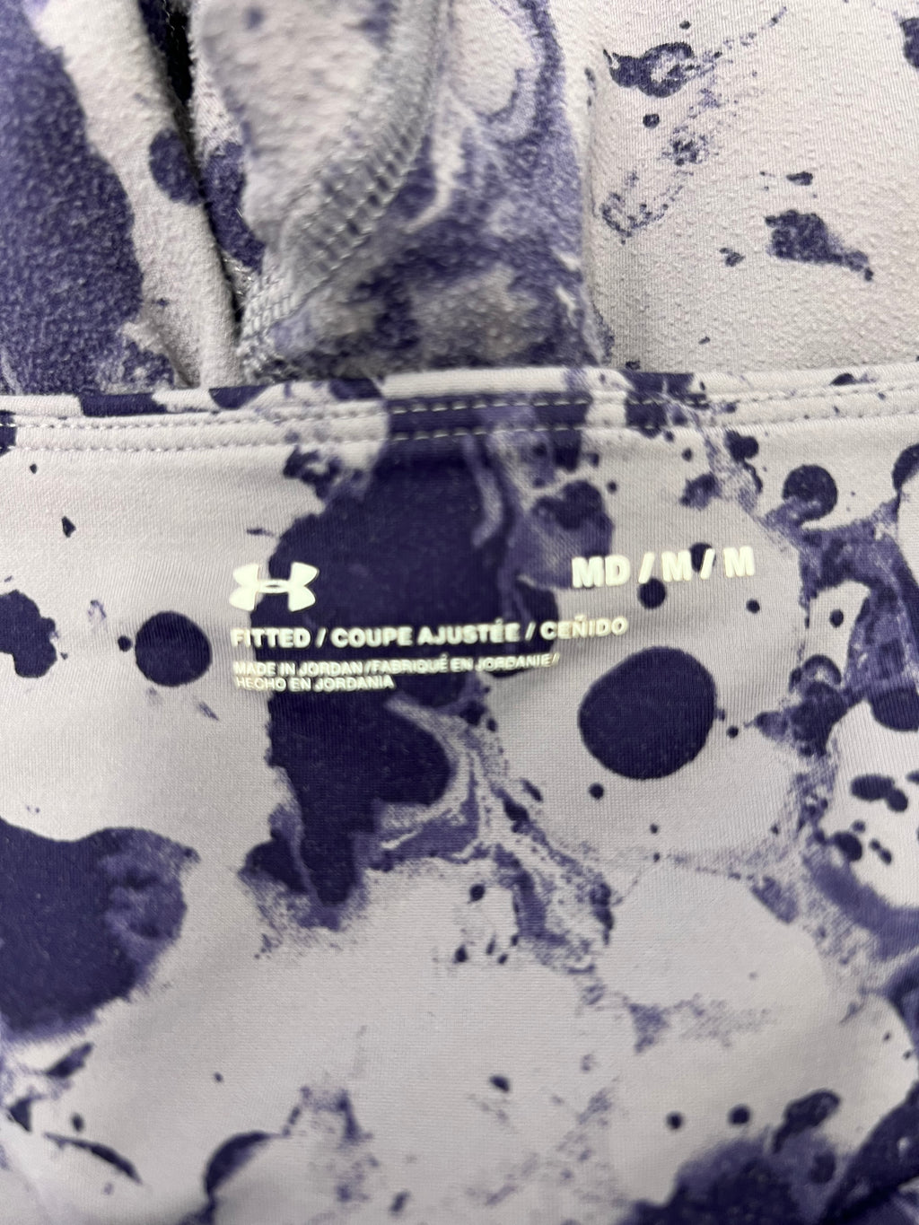 Close-up of waistband label inside Under Armour fitted leggings showing size Medium and product details