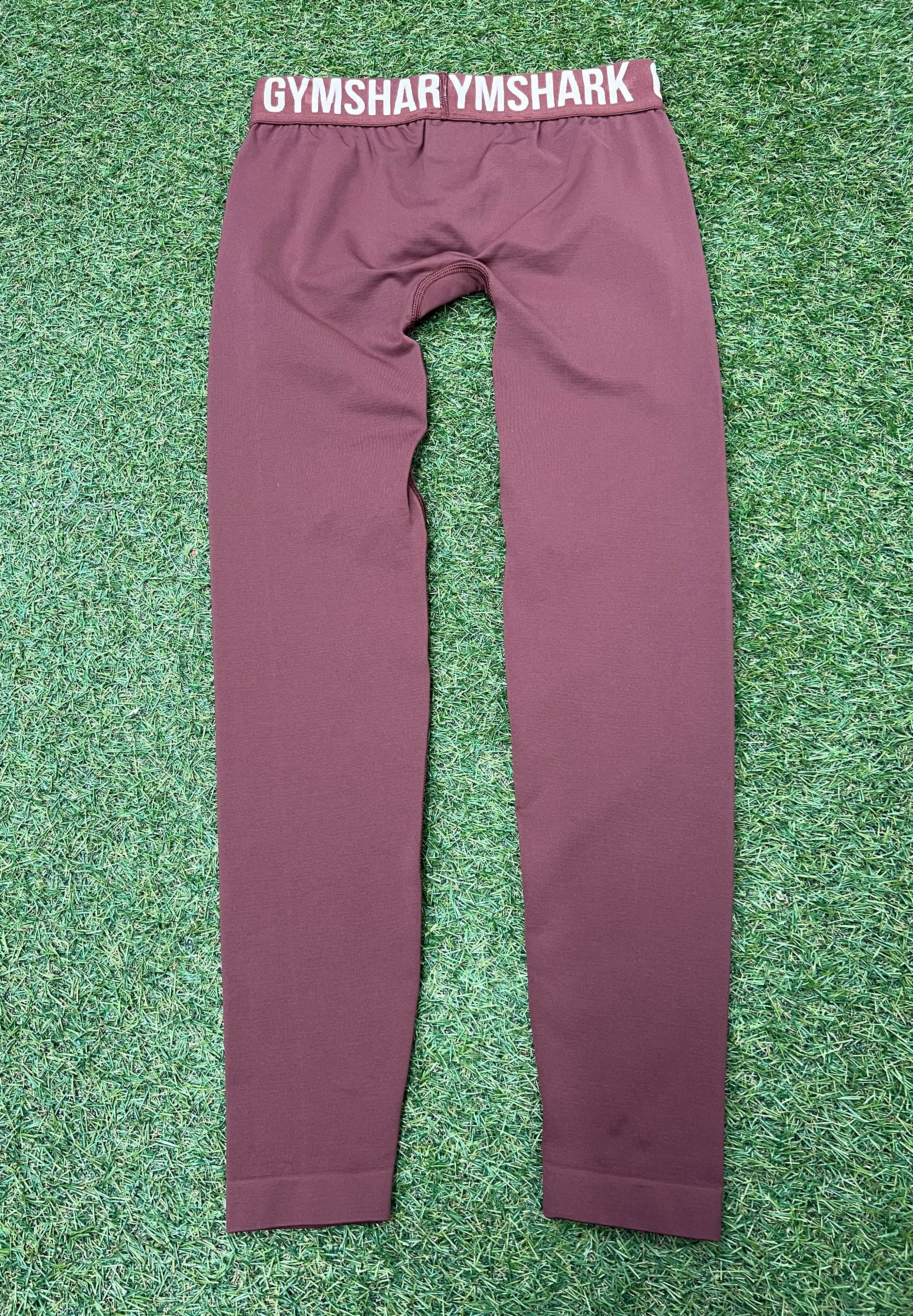 Back view of maroon Gymshark leggings laid flat on grass highlighting the clean, seamless design
