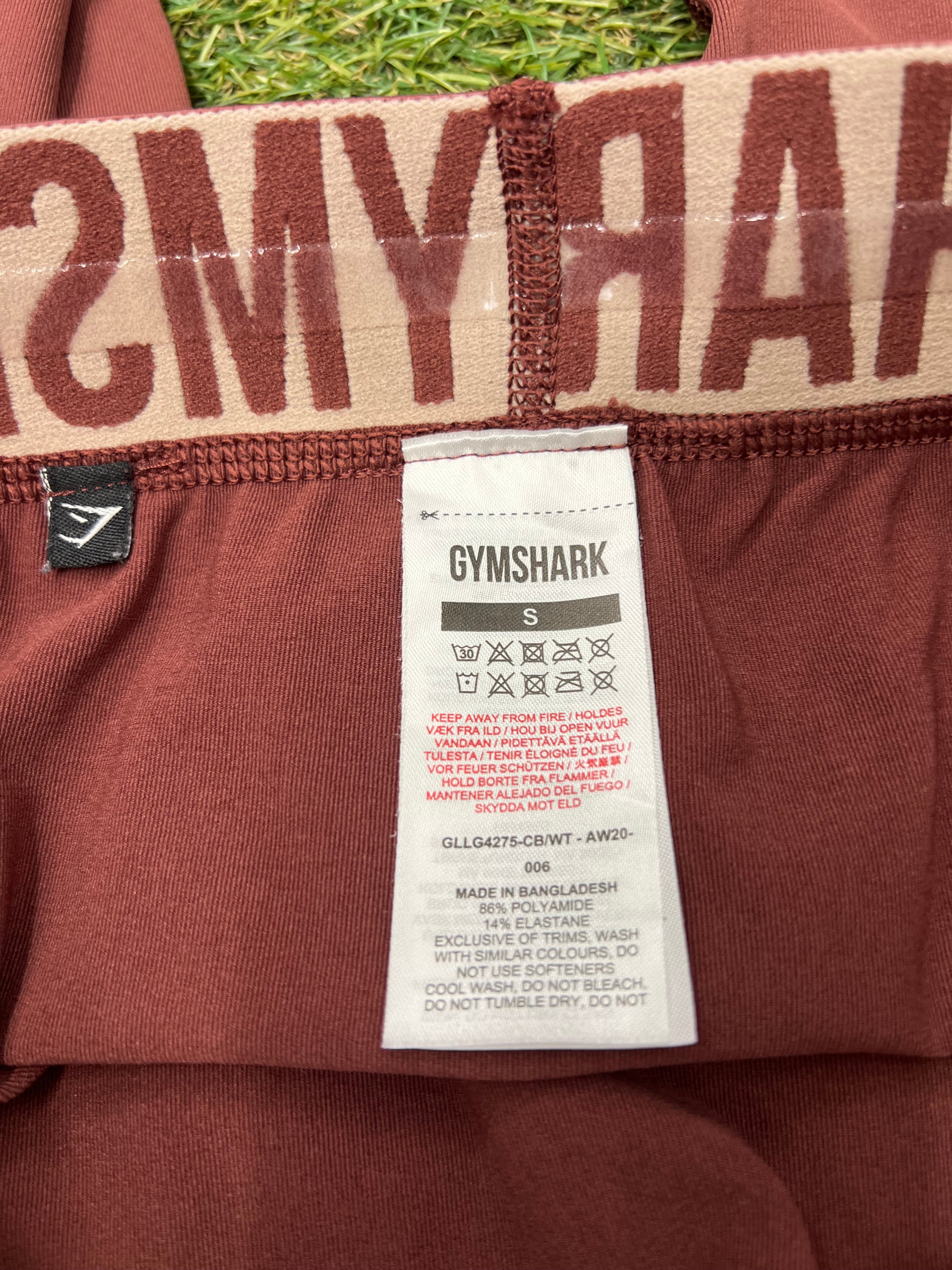 Close-up of care and material label inside maroon Gymshark leggings showing fabric content and washing instructions
