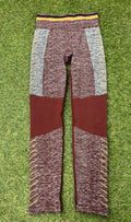 Front view of maroon and grey seamless Sweaty Betty leggings with yellow detailing on grass background