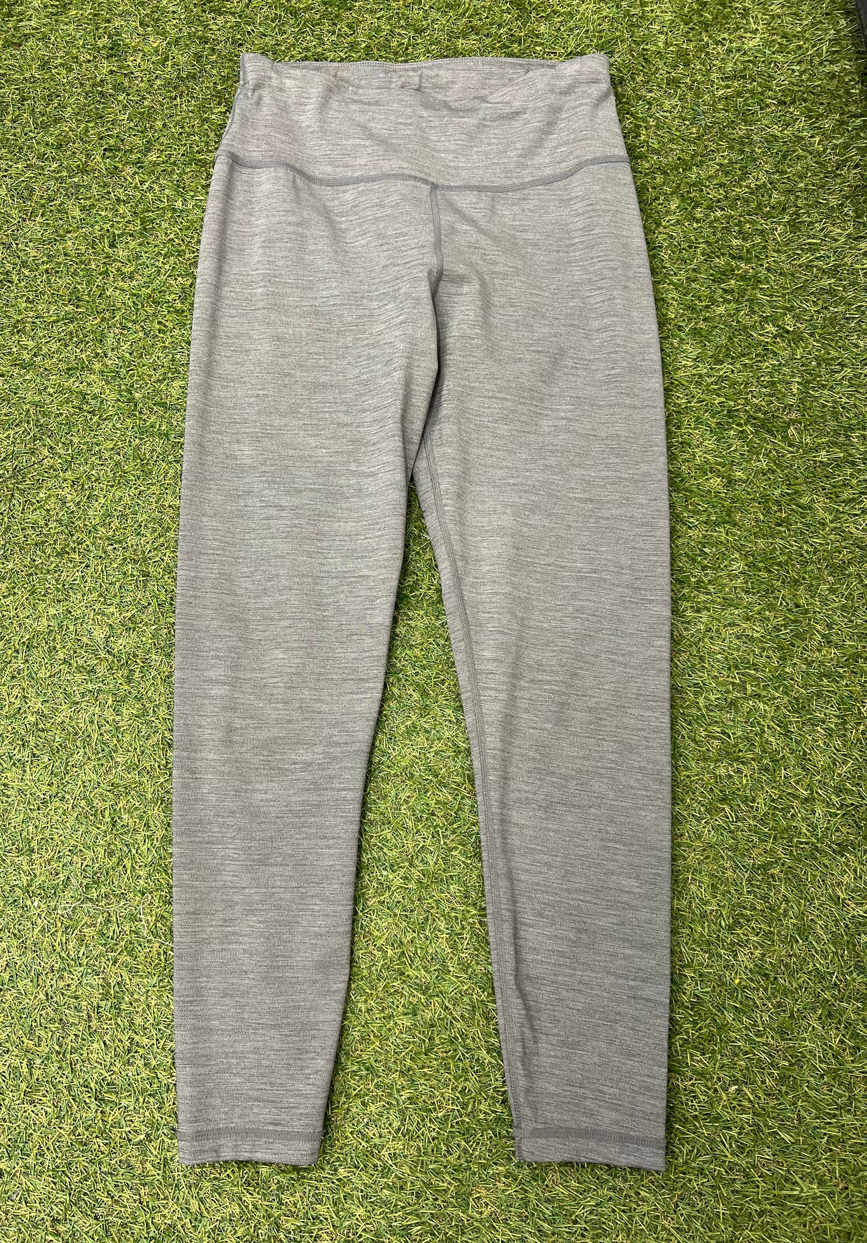 Front view of grey Sweaty Betty leggings laid flat on grass surface