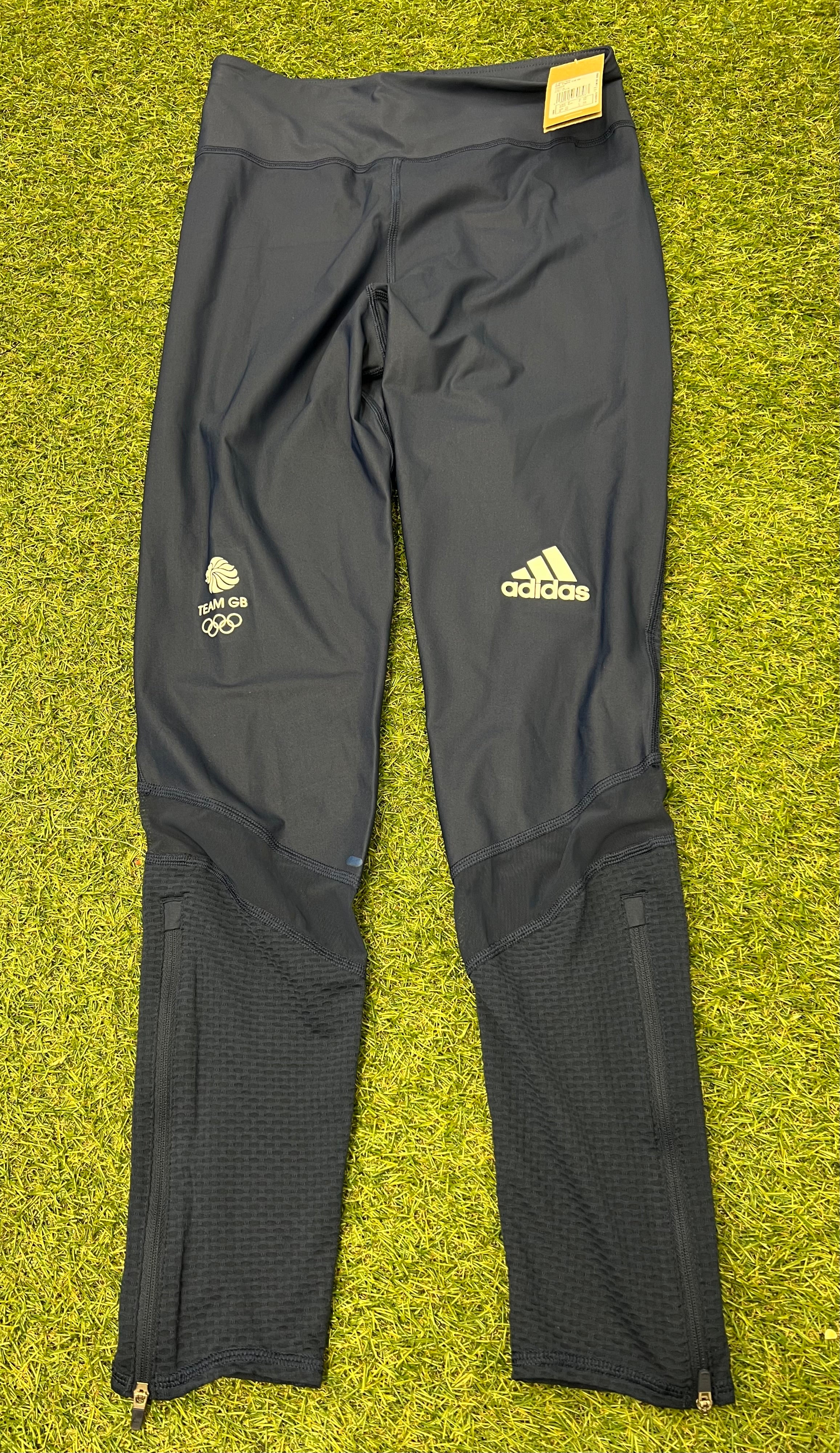 Front view of black Adidas Team GB 7/8 tights laid flat on grass with Team GB and Adidas logos visible