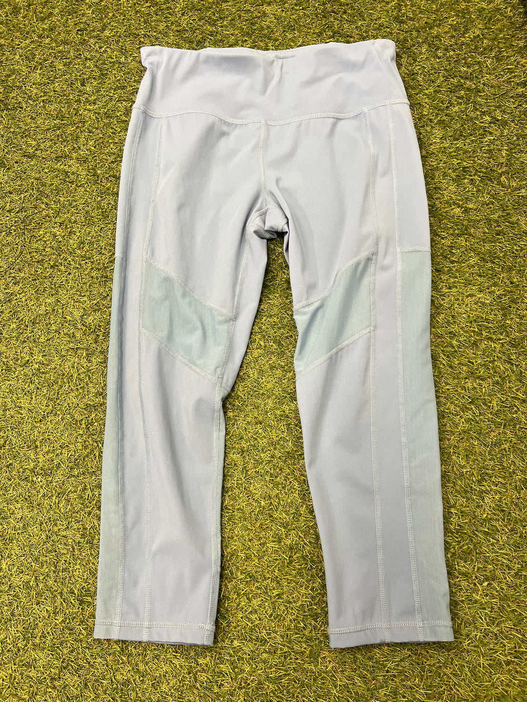 Front view of pale grey Sweaty Betty leggings with mesh inserts laid on grass