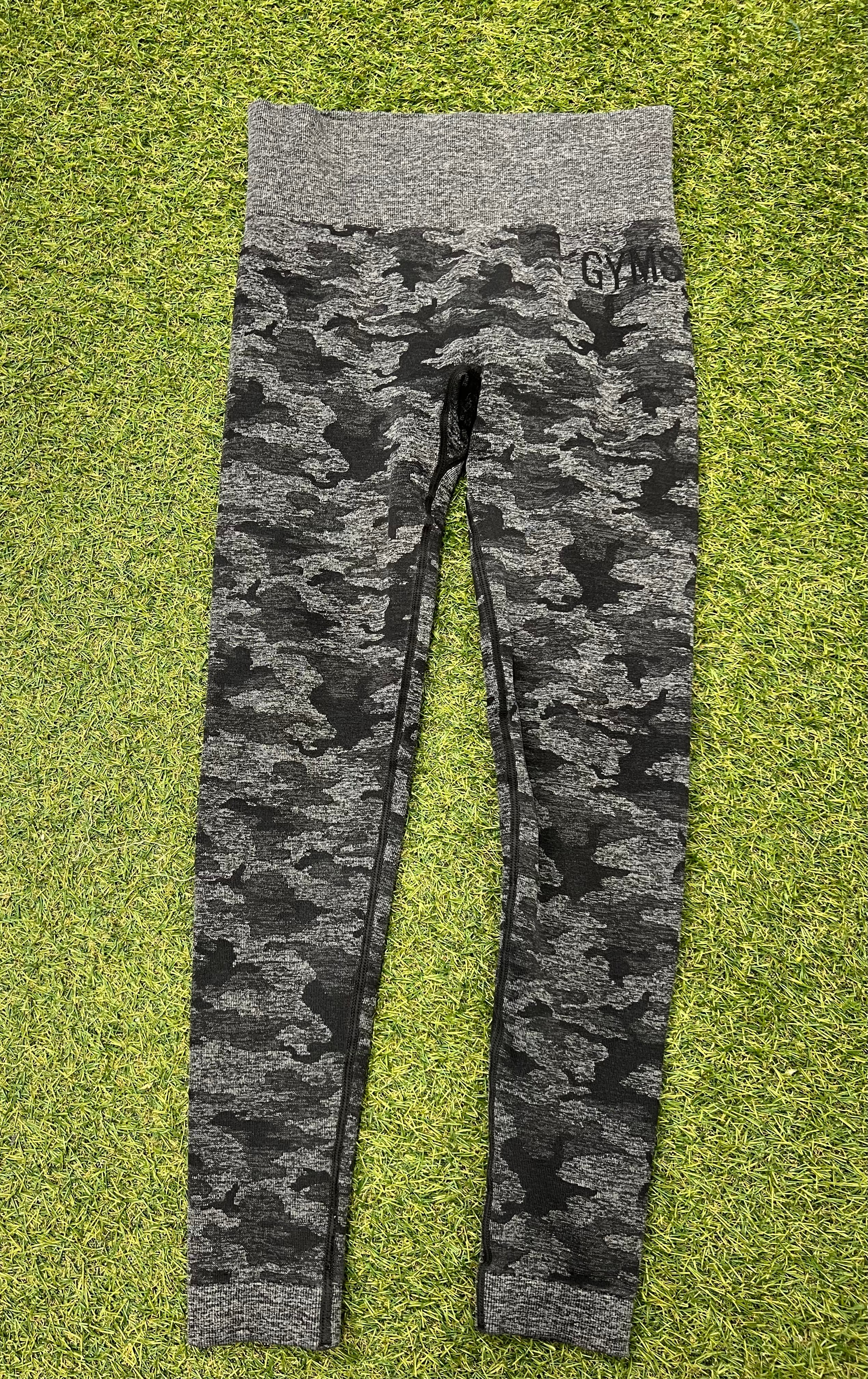 Front view of Gymshark grey camouflage active leggings laid flat on grass