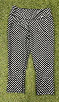 Front view of Nike Dri-FIT black and white zigzag patterned crop leggings laid flat on grass