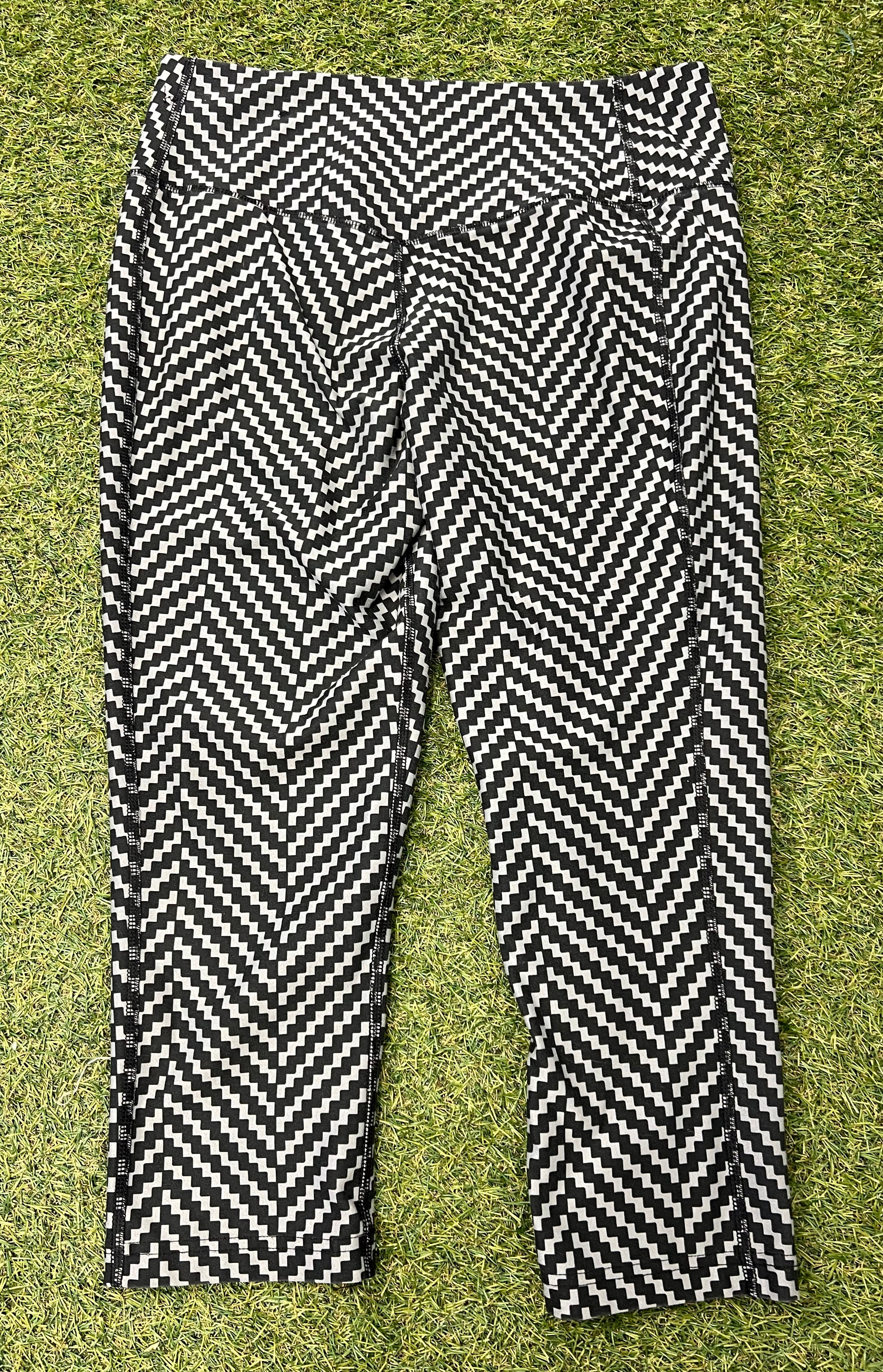 Back view of Nike Dri-FIT black and white zigzag patterned crop leggings showing high-rise waist and seams