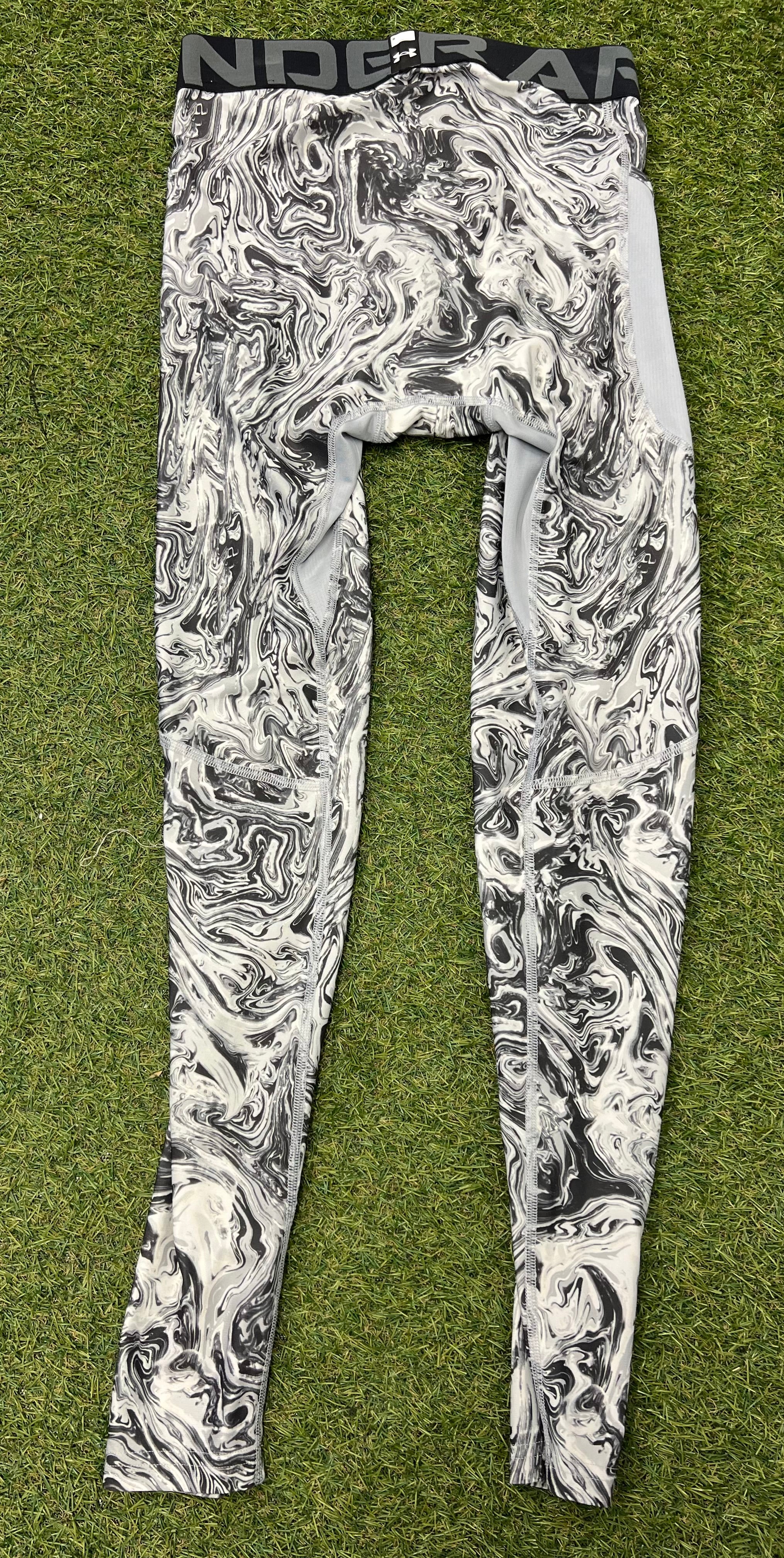 Back view of Under Armour mens compression tights highlighting marbled pattern and mesh ventilation panels on grass background