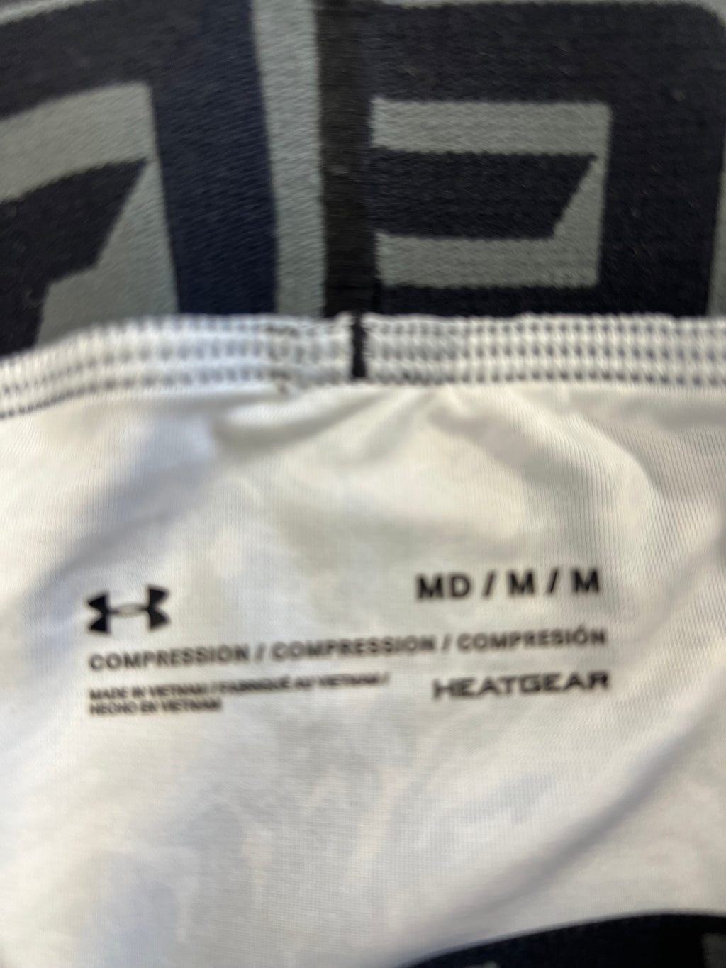 Close-up of inner label of Under Armour compression tights showing size medium and HeatGear thermal technology branding