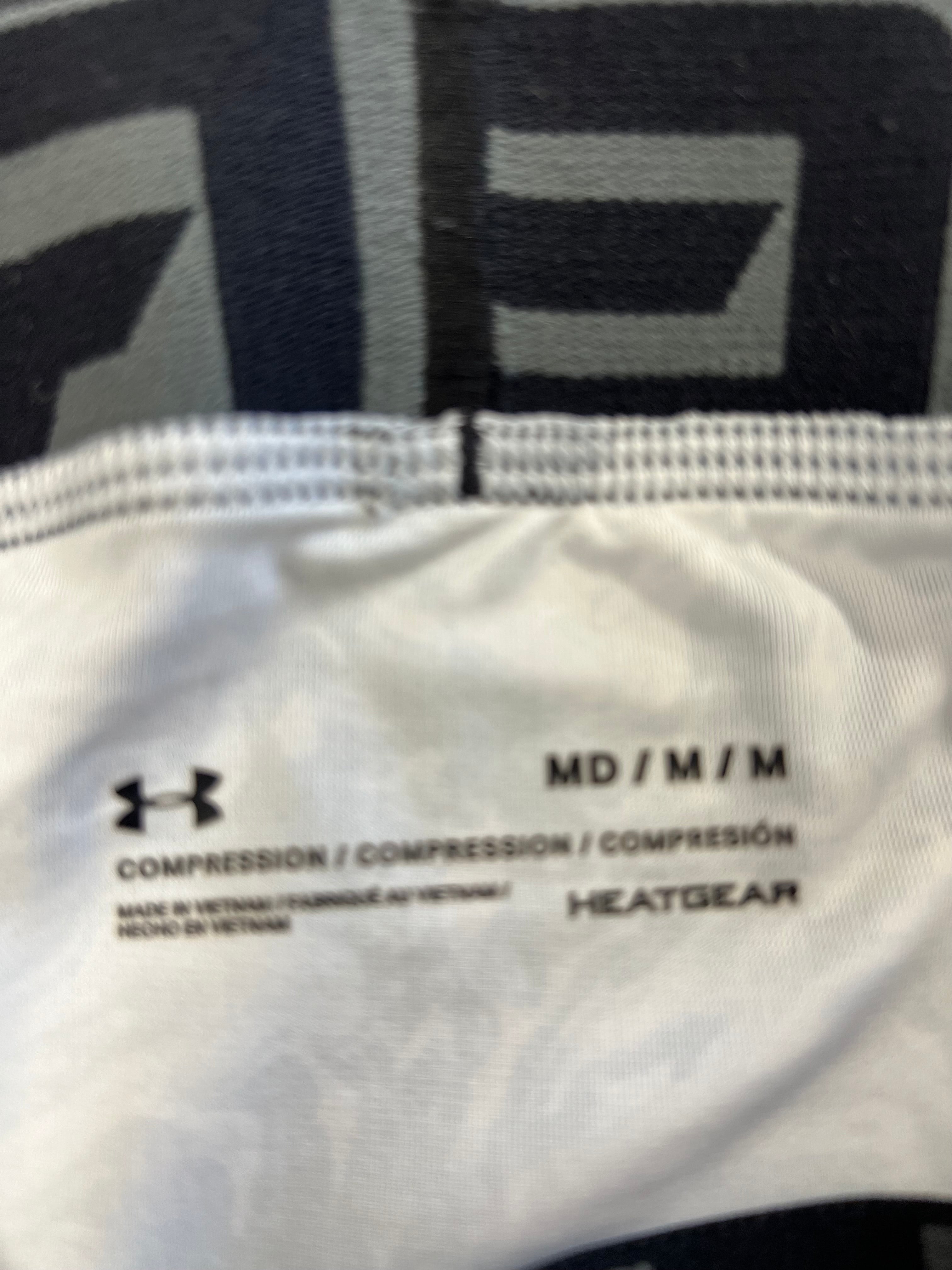 Close-up of inner label of Under Armour compression tights showing size medium and HeatGear thermal technology branding