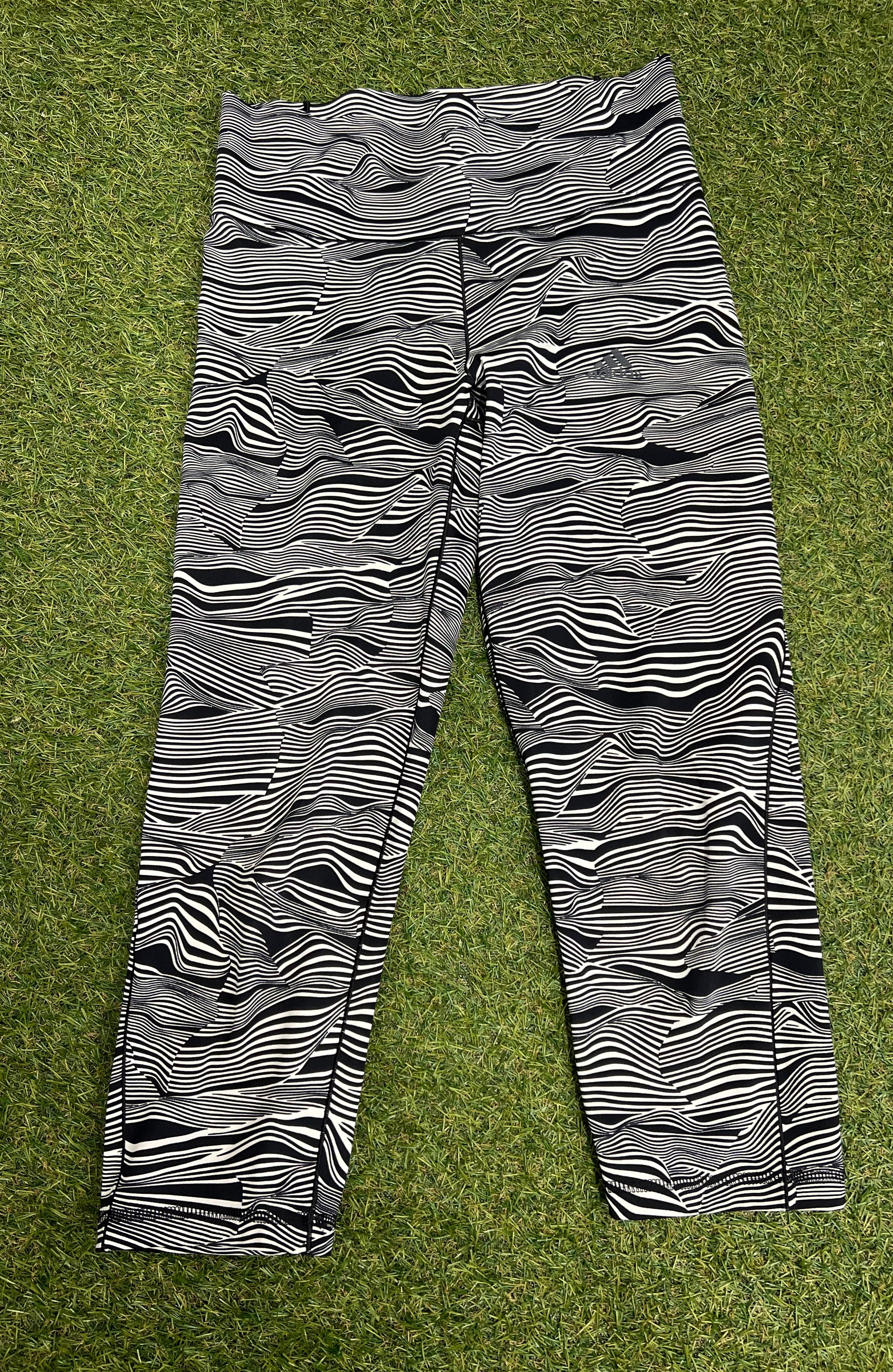 Front view of Adidas 7/8 leggings with black and white abstract wave pattern laid on grass surface