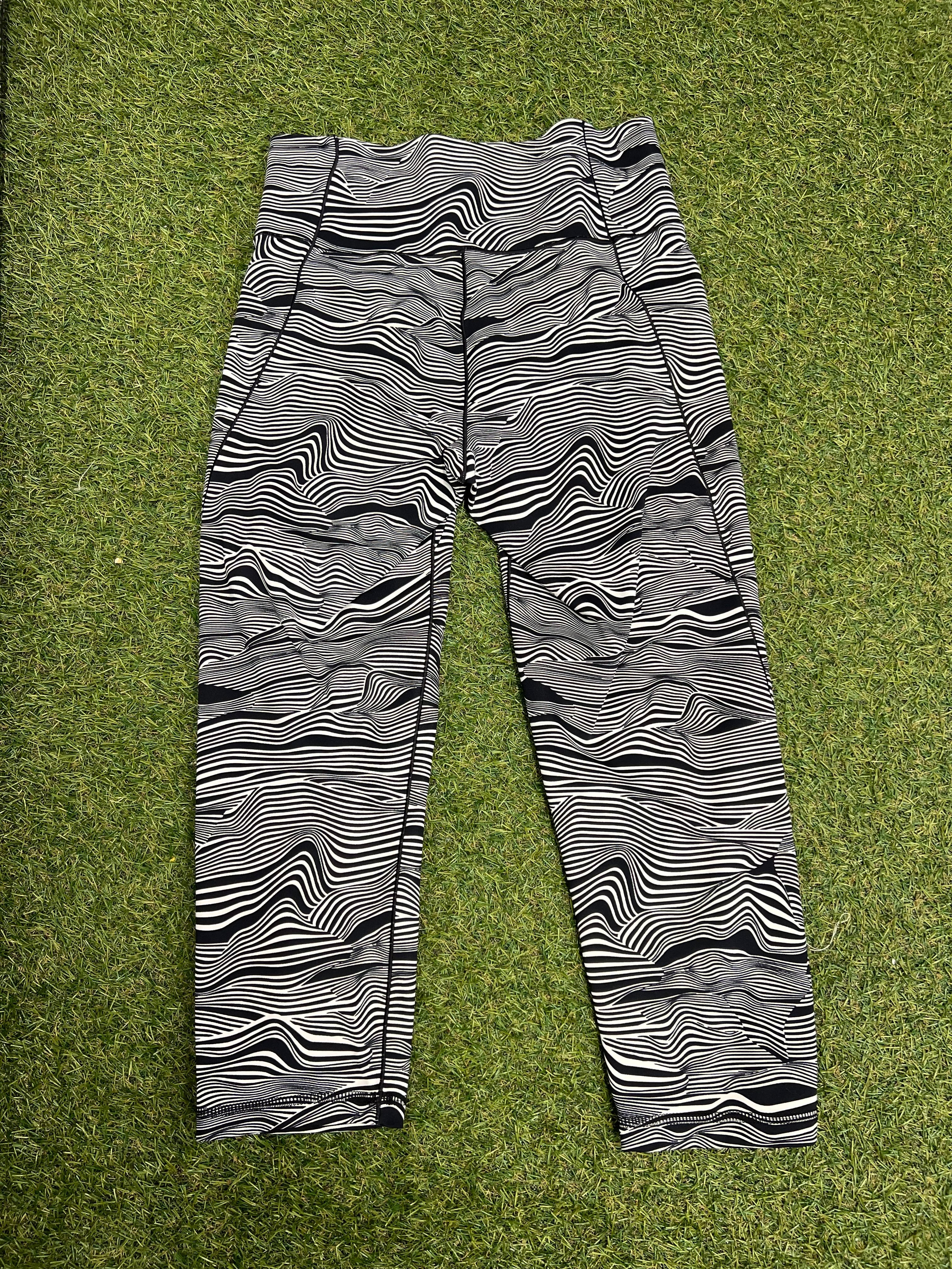 Back view of Adidas 7/8 leggings featuring black and white abstract print lying on grass