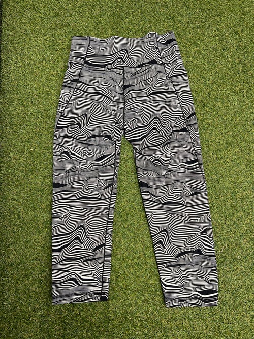 Back view of Adidas 7/8 leggings featuring black and white abstract print lying on grass