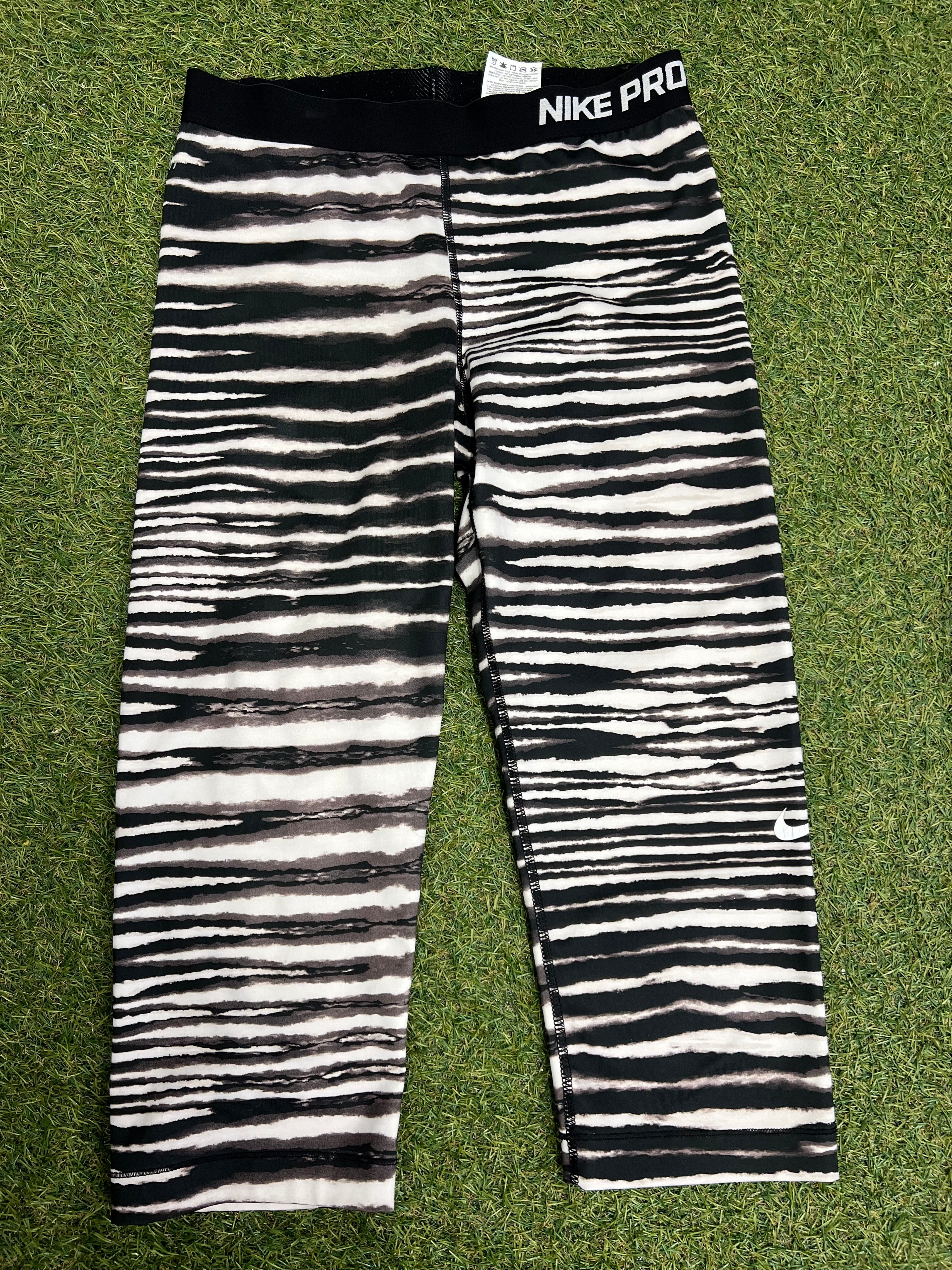 Front view of black and white striped Nike Pro 7/8 leggings laid flat on grass