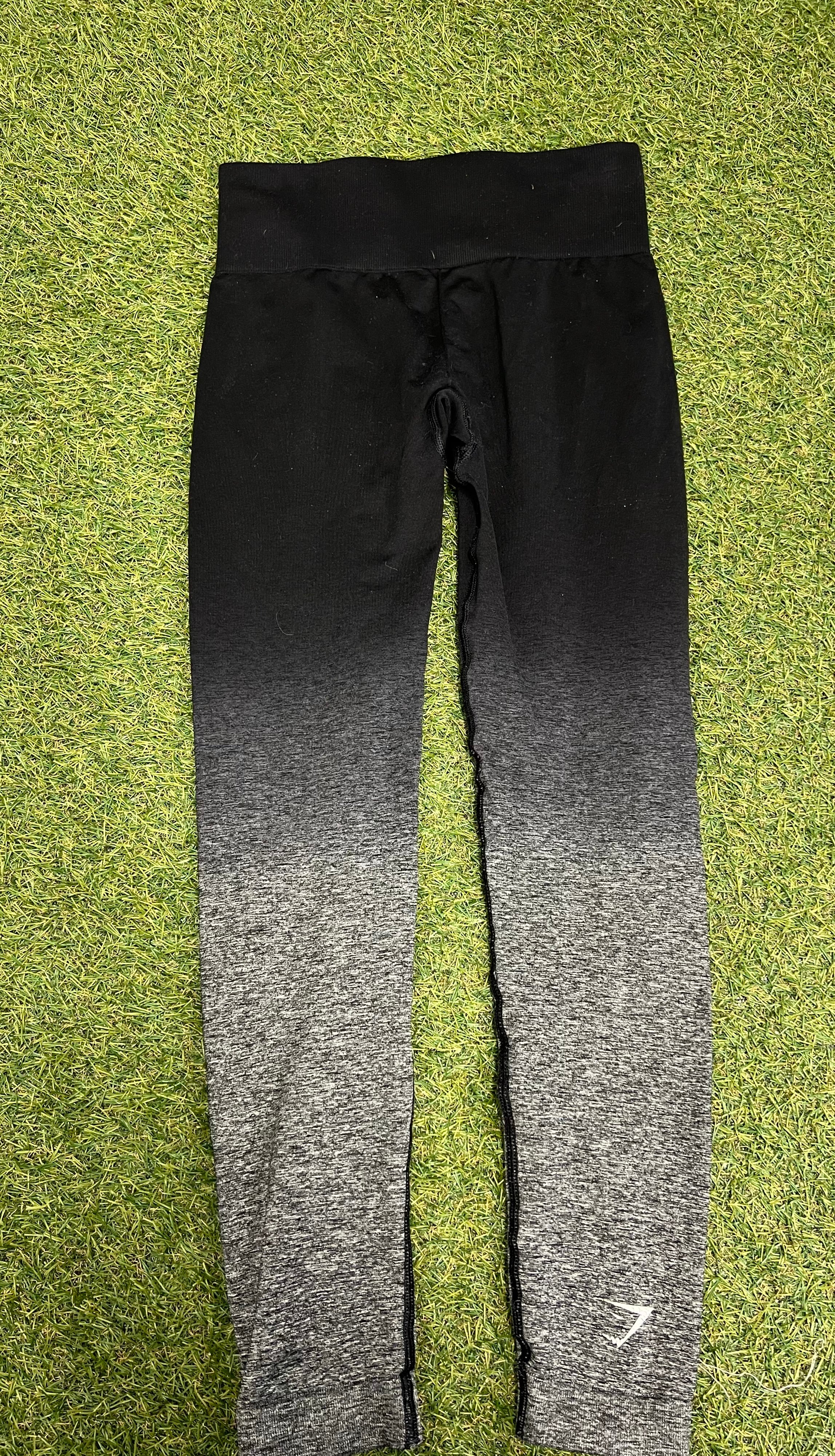 Back view of Gymshark Ombre Seamless Leggings on grass, highlighting wide waistband and subtle ankle logo