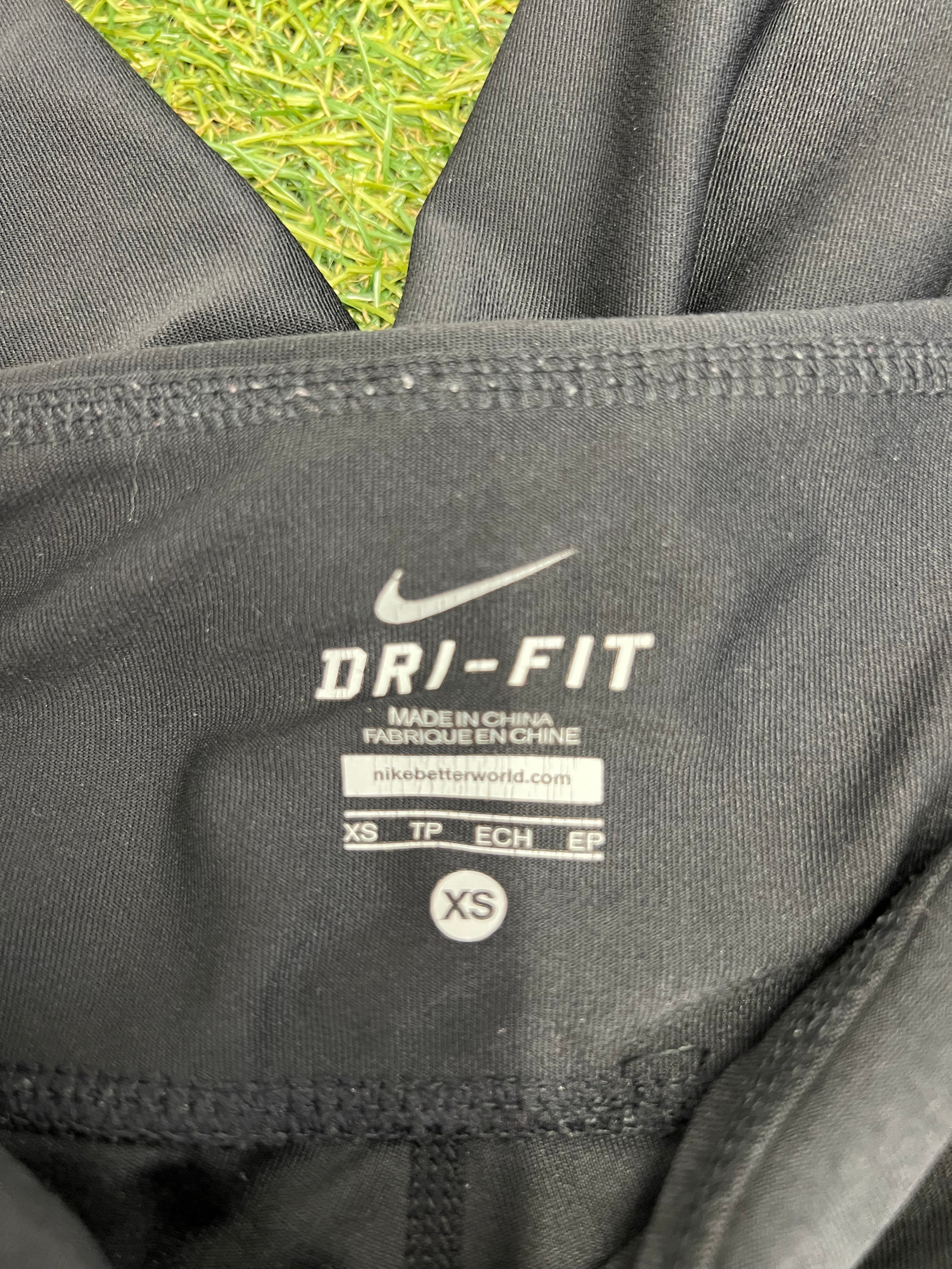Close-up inside label of Nike Dri-FIT leggings showing size XS and manufacturing details