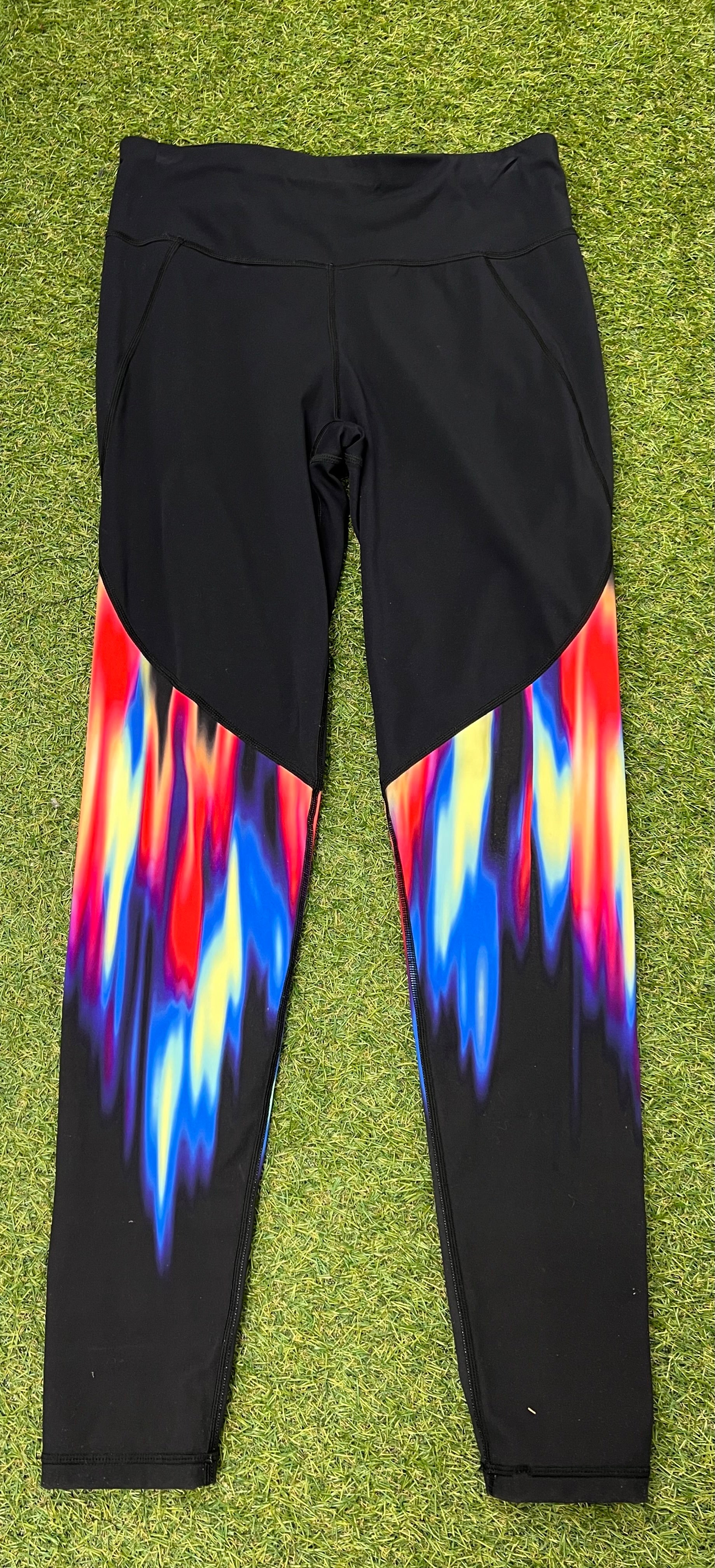 Front view of black gym leggings with bright red, blue, yellow and purple abstract pattern on lower legs